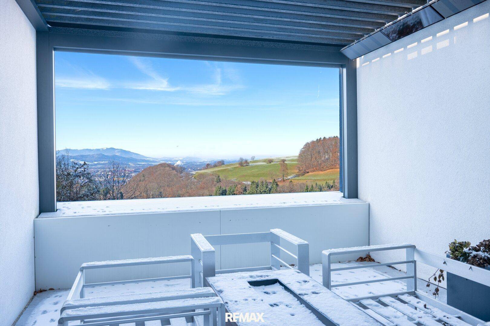 Überdachte Terrasse mit Sitzgelegenheiten und weitem Panoramablick über die winterliche Landschaft.