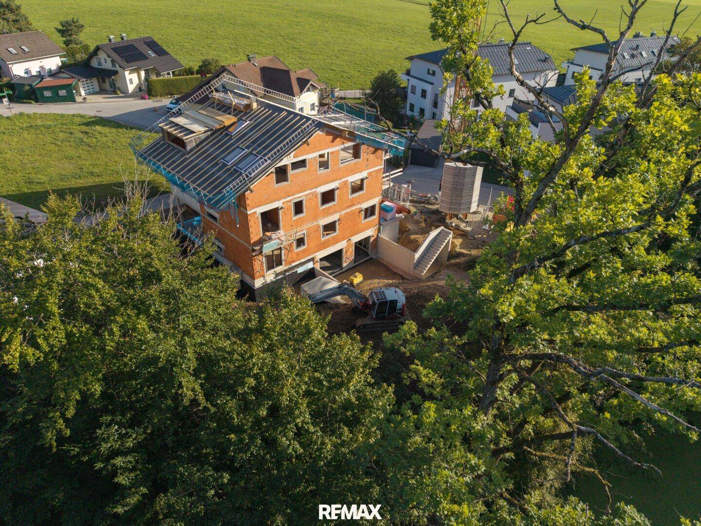 Luftaufnahme des im Bau befindlichen Hauses, umgeben von Bäumen und grünen Flächen in ländlicher Umgebung.