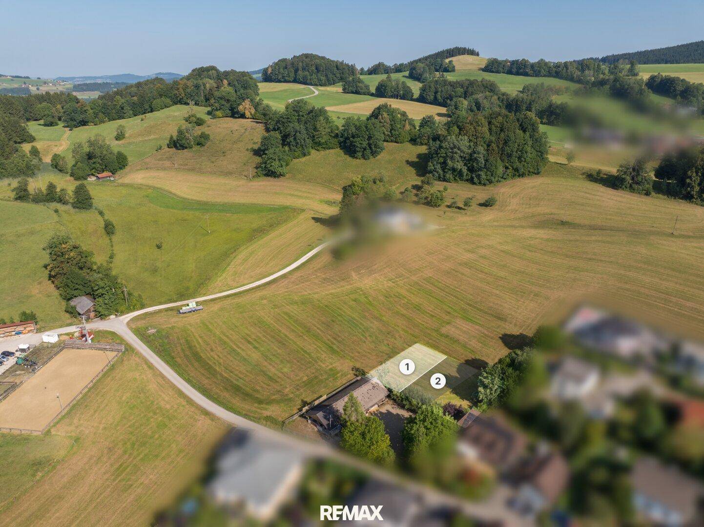 Panoramablick aus der Vogelperspektive auf ein Grundstück umgeben von grünen Hügeln und Feldern.