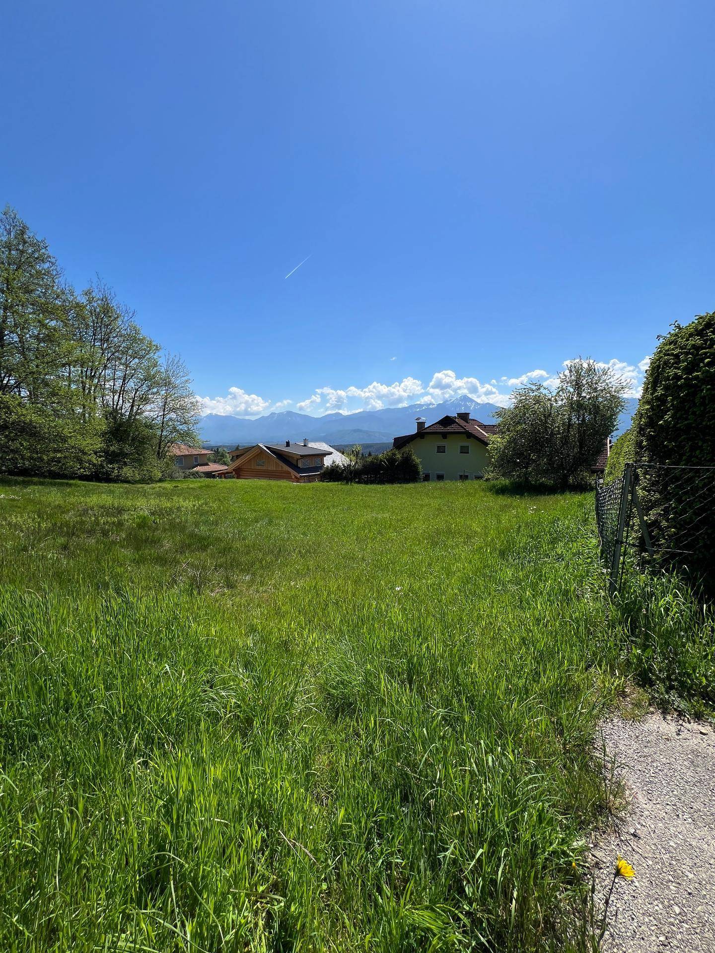 Großes grünes Grundstück mit Panoramablick auf die Bergkette und angrenzendem Weg.