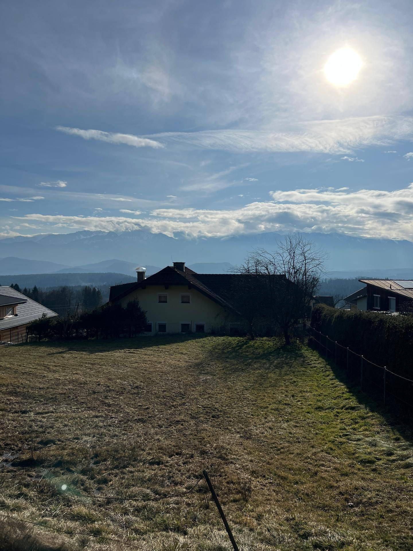 Grundstück mit Blick auf die Berge und umliegende Häuser an einem klaren, sonnigen Wintertag.