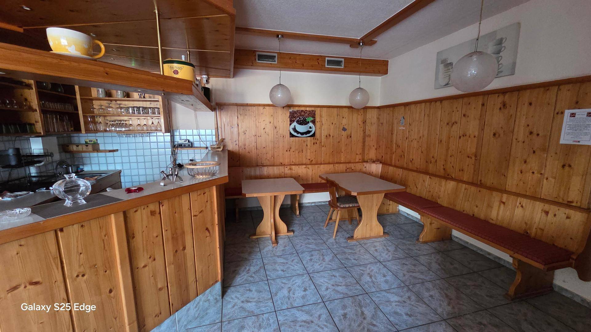 Gemütlicher Essbereich mit Holzbänken, Tischen und traditioneller Holzvertäfelung an den Wänden.
