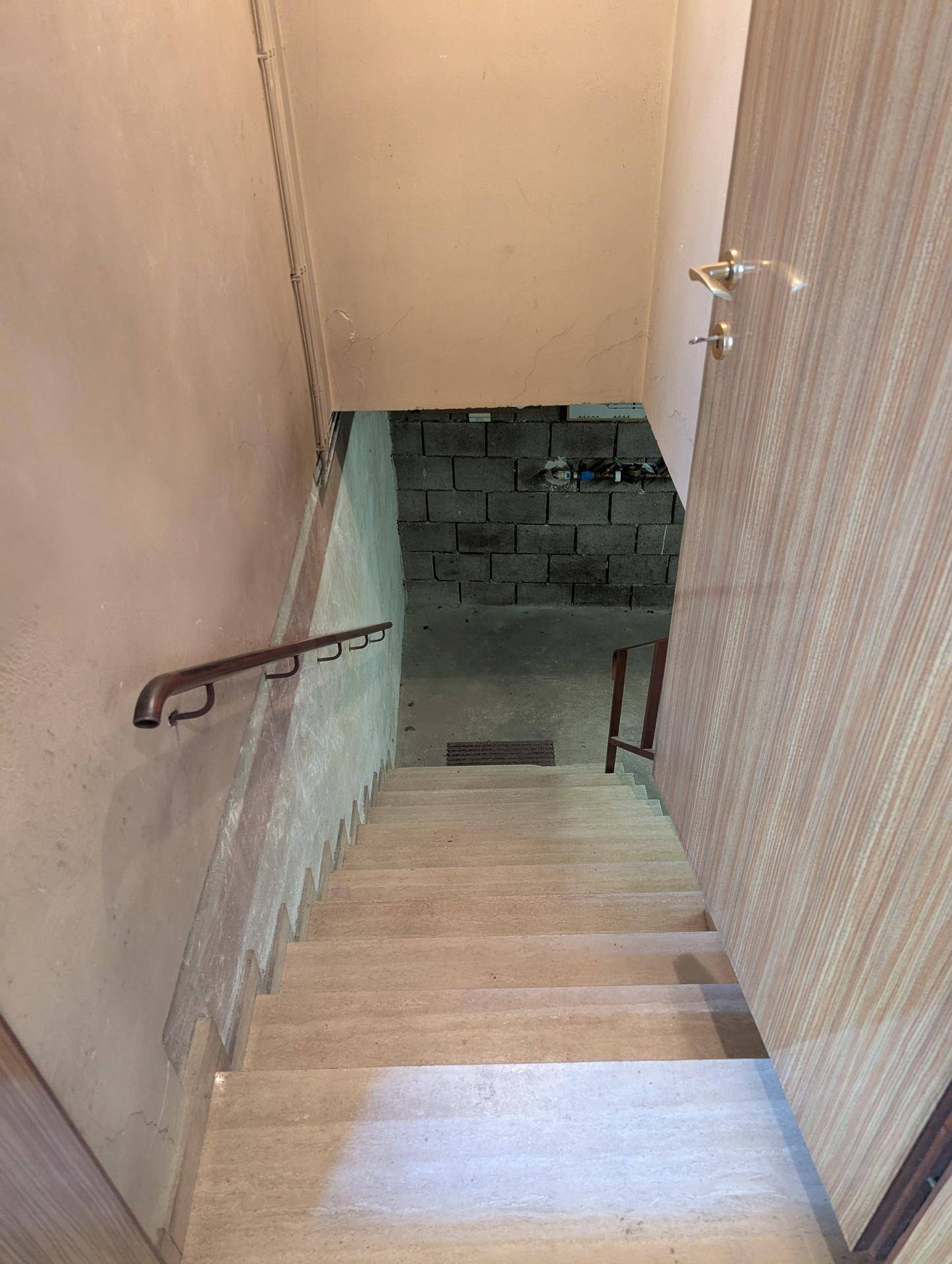 Treppe führt in den Kellerbereich mit unverputzten Wänden.