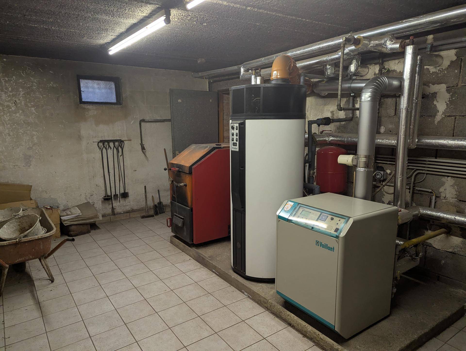 Heizungsraum im Keller mit verschiedenen Heizungsanlagen und Rohren.