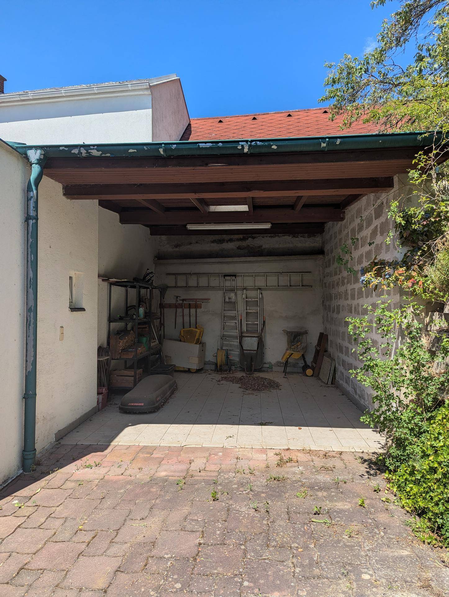 Überdachter Außenbereich oder Carport mit Lagerfläche und Werkzeugen.