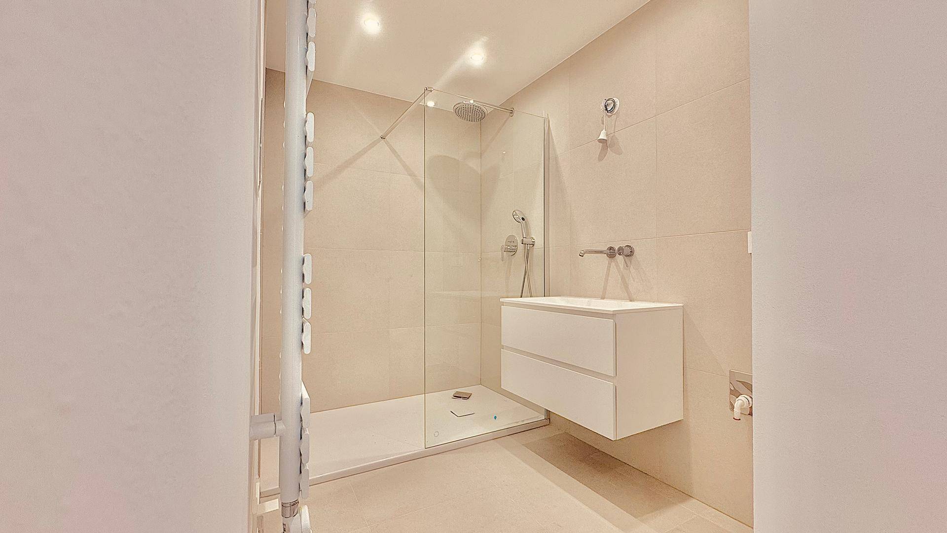 Modernes Badezimmer mit begehbarer Dusche, schwebendem Waschtisch und beheiztem Handtuchhalter.