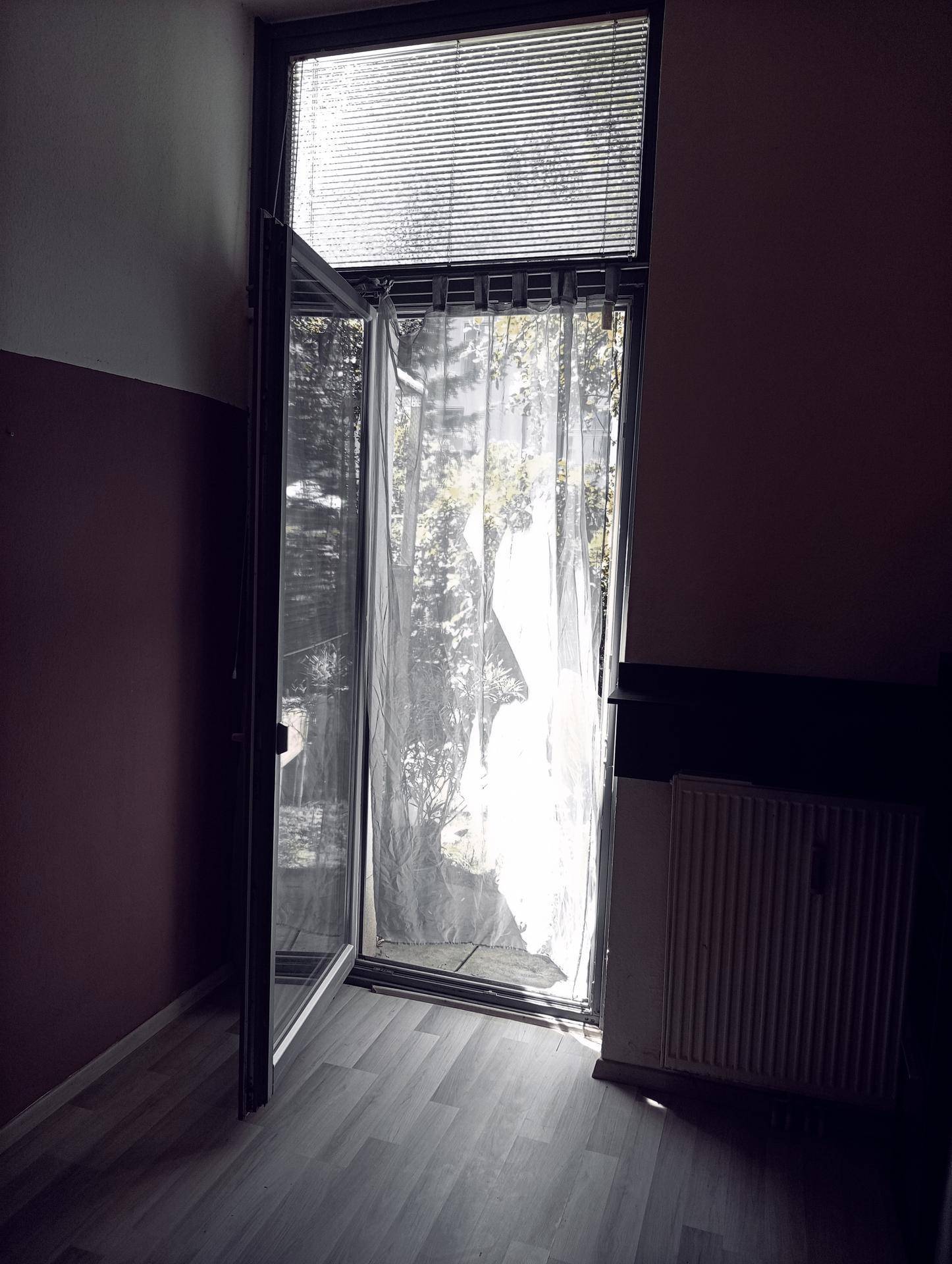 Helles Schlafzimmer mit geöffnetem Fenster, das viel natürliches Licht und einen Blick ins Grüne bietet.