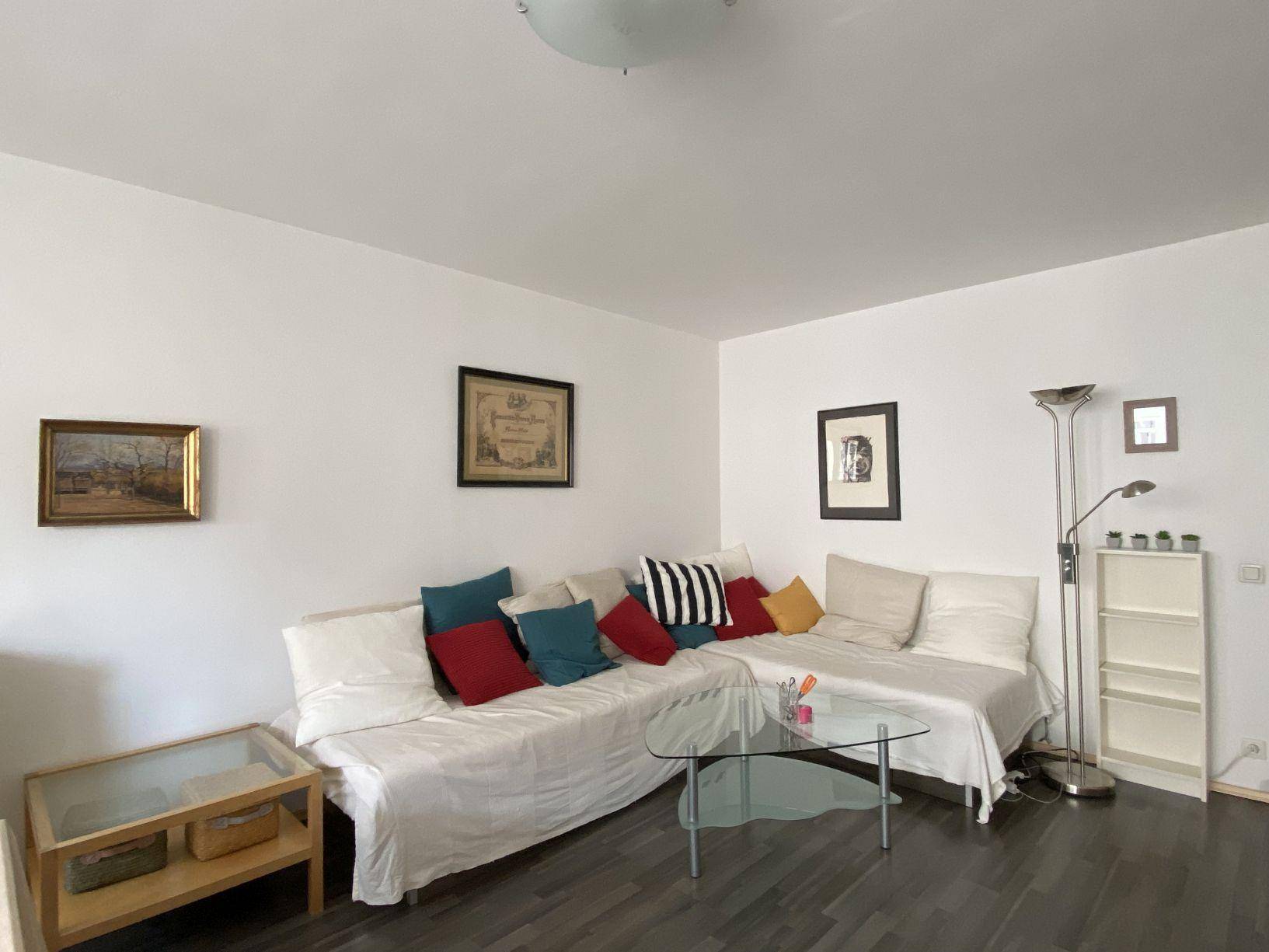 Gemütliches Wohnzimmer mit großem Sofa, Couchtisch und dunklem Laminatboden.