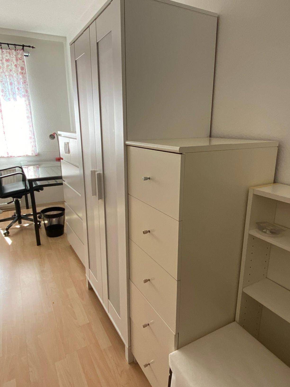 Detailansicht des Schlafzimmers mit hellem Kleiderschrank, Kommode und Schreibtisch am Fenster.