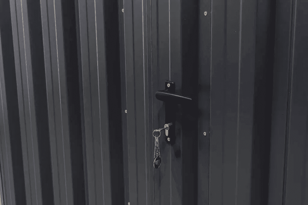 Nahaufnahme einer verschlossenen Metalltür eines Lagercontainers mit Schlüssel im Schloss.