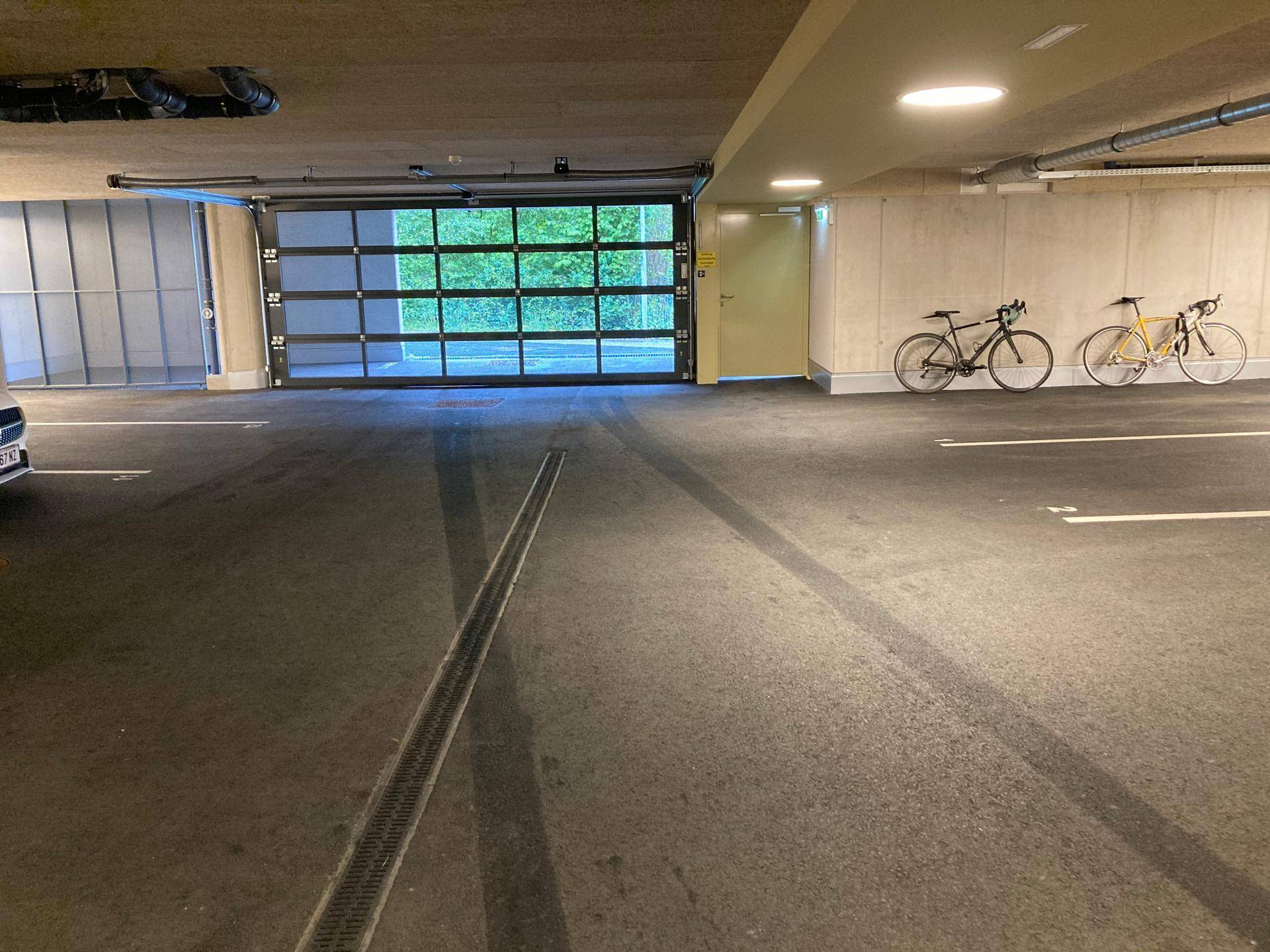 Tiefgarageneinfahrt mit Tageslicht, Abstellmöglichkeiten für Fahrräder und sauberem Betonboden.