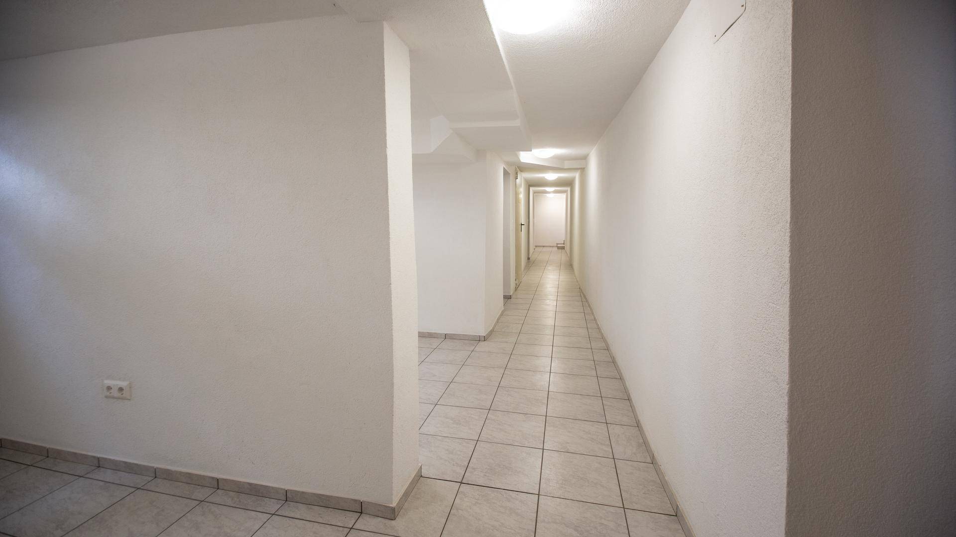 Langer, gefliester Flur im Kellergeschoss mit mehreren Zugängen zu den Kellerräumen.