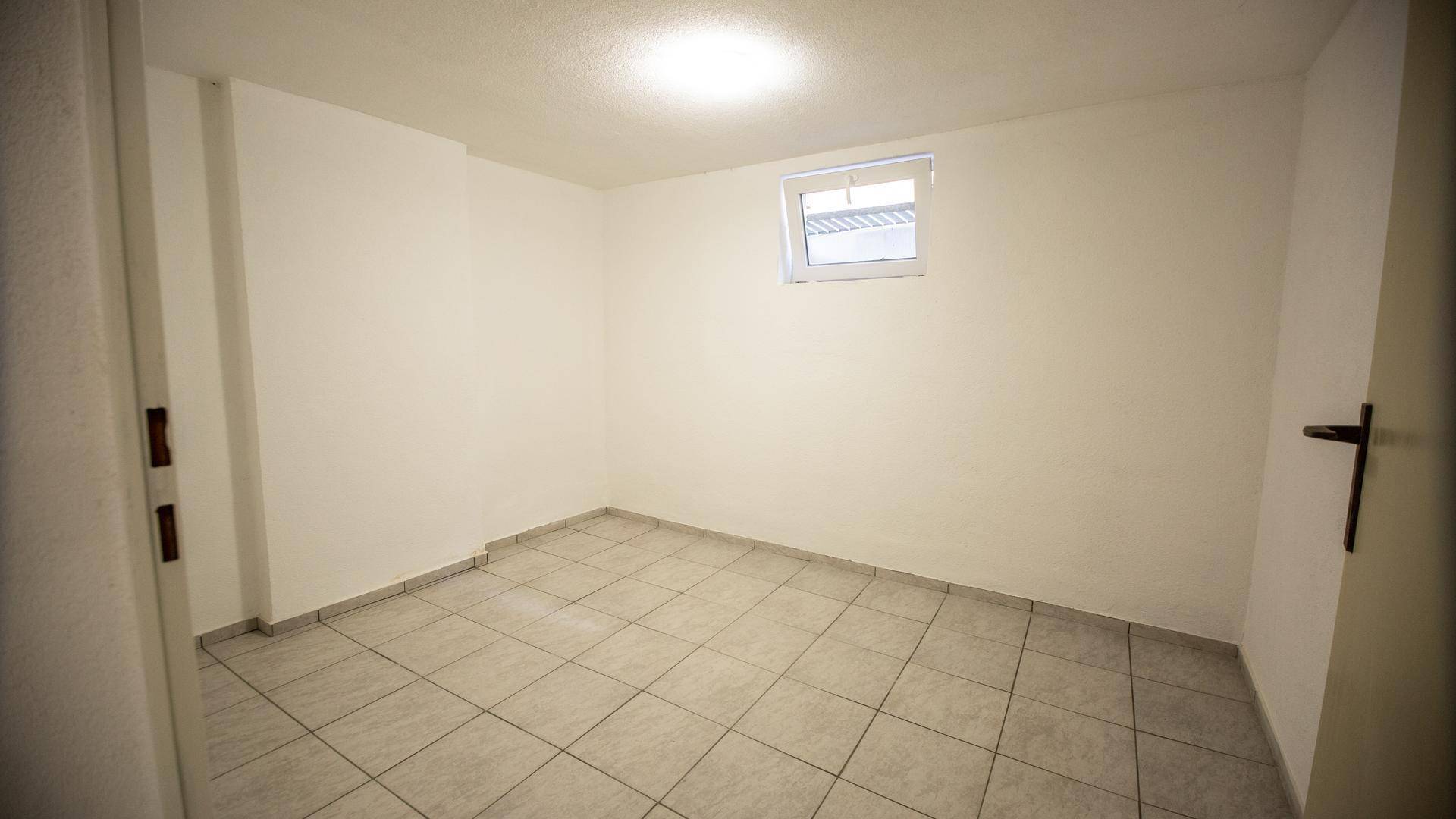 Heller Kellerraum mit Fliesenboden und kleinem Fenster, ideal als Abstellraum nutzbar.