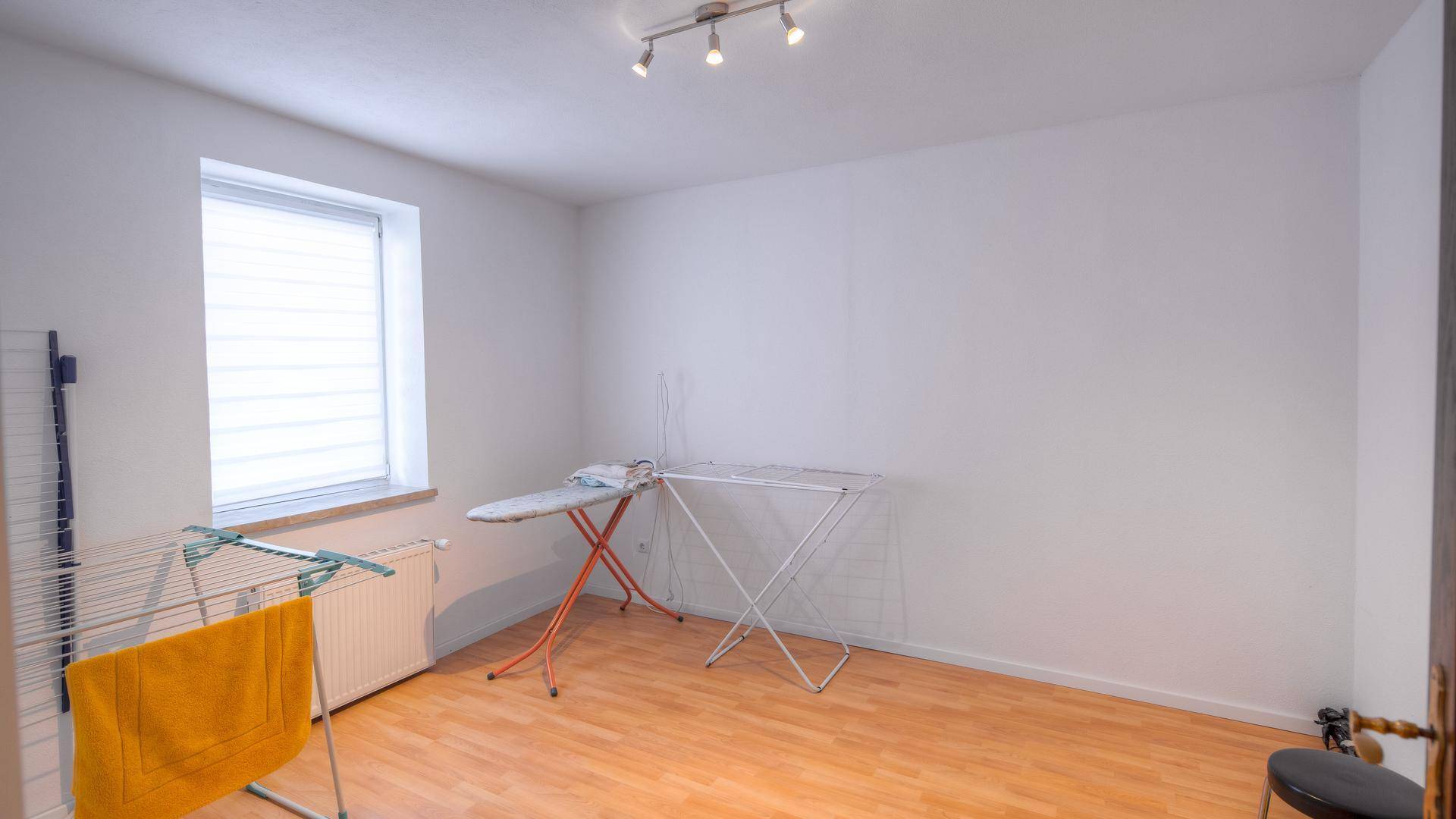 Praktischer Hauswirtschaftsraum mit Fenster, Bügelbrett und Wäscheständer für den Alltag.