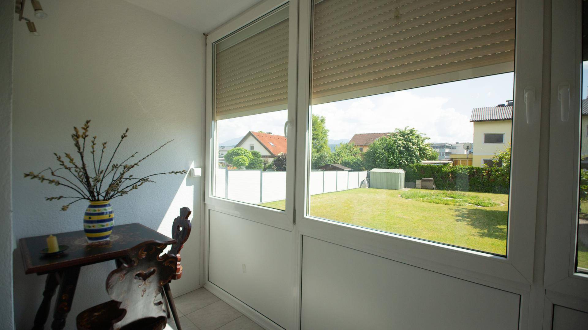 Heller, verglaster Balkon mit Blick auf den Garten und die umliegende Nachbarschaft.