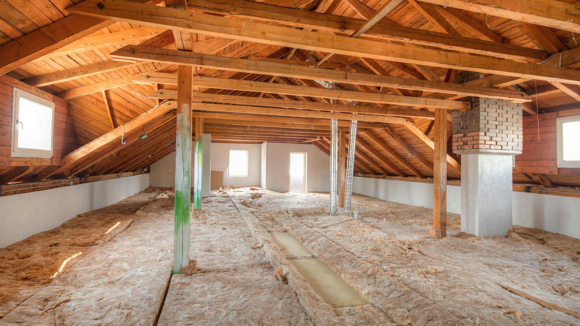 Geräumiger Dachboden mit sichtbaren Holzbalken und Isolierung, bereit für den Ausbau.