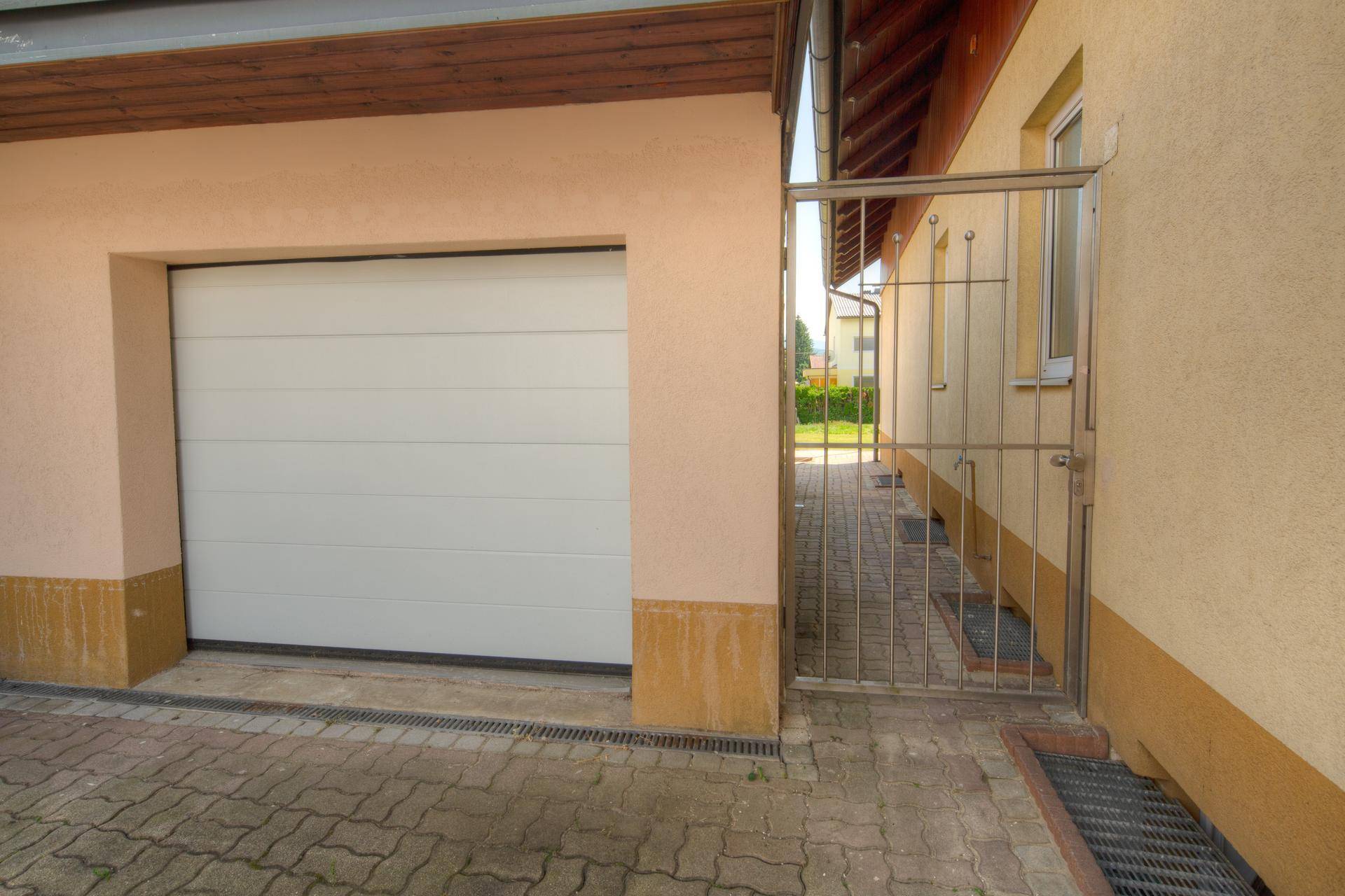 Weiße Garagentür und ein Metalltor, das zu einem Seitenweg des Hauses führt.