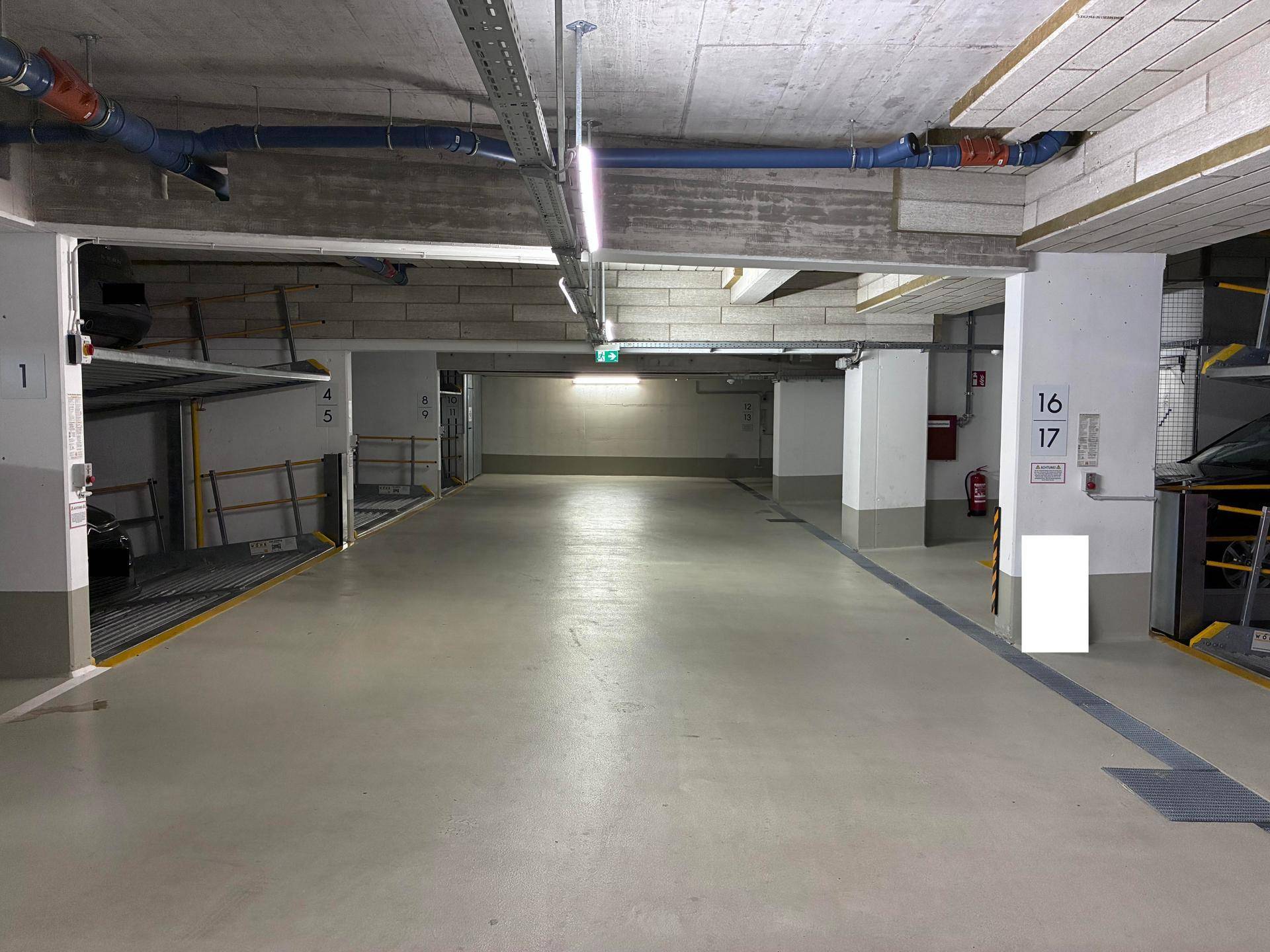 Geräumige und gut beleuchtete Tiefgarage mit Betonwänden und nummerierten Parkplätzen.
