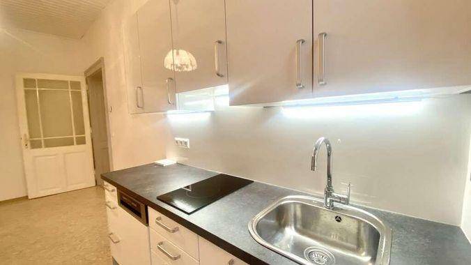 Moderne Küche mit weißen Hochglanzschränken, dunkler Arbeitsplatte und integriertem Induktionskochfeld.