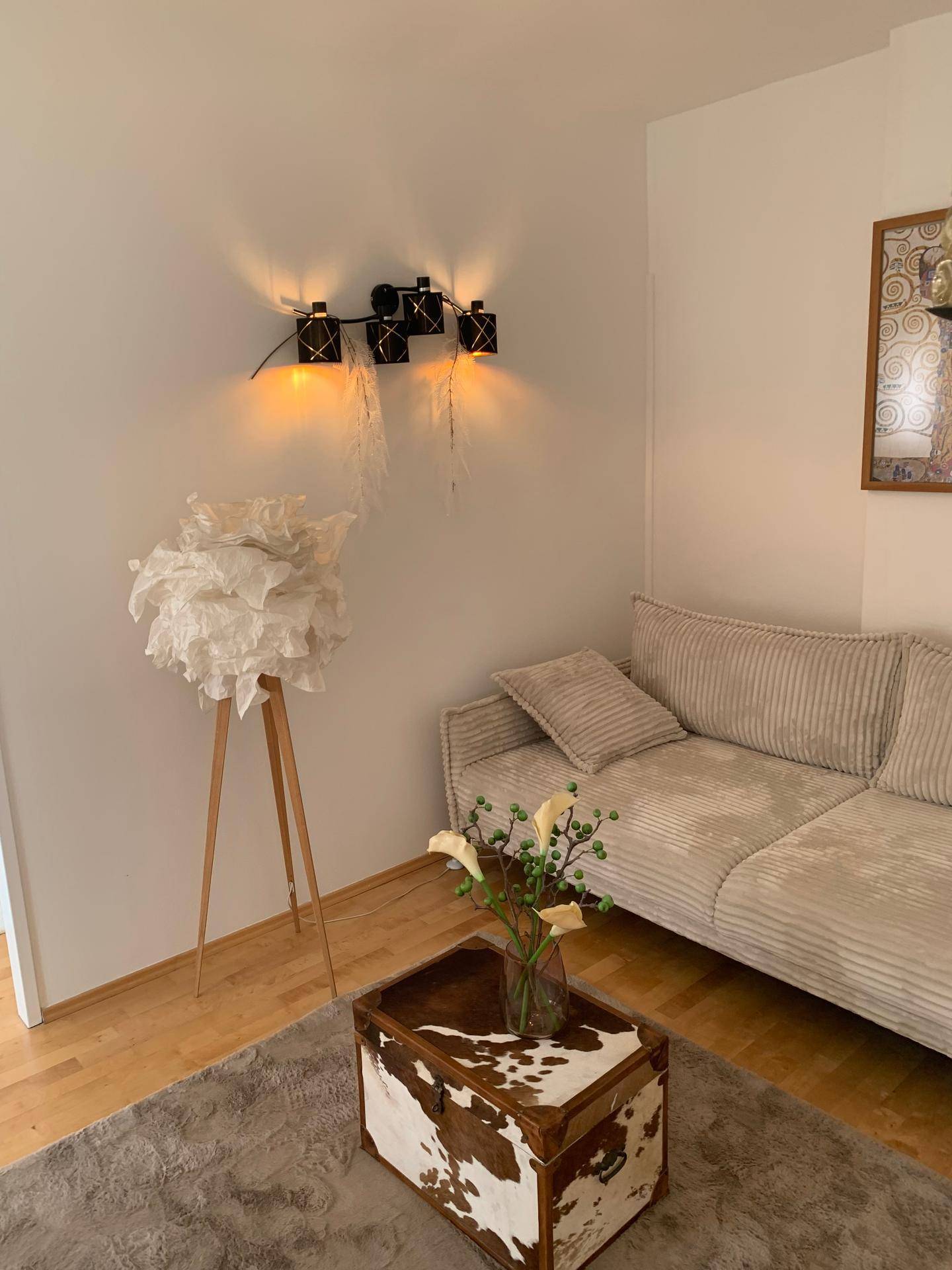 Heller Wohnbereich mit bequemem Sofa, einzigartiger Stehlampe und Kunstwerk an der Wand.