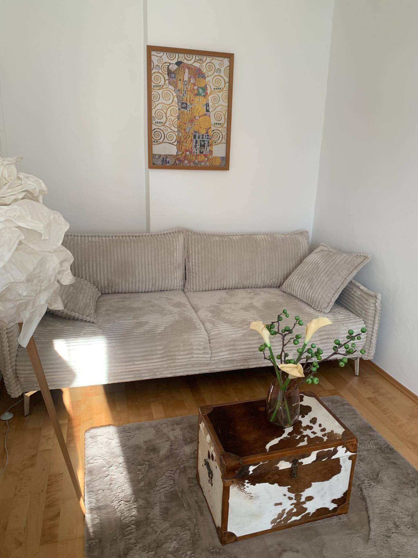 Gemütliches Wohnzimmer mit beigem Sofa, Fell-Couchtisch und Kunstwerk an der Wand.
