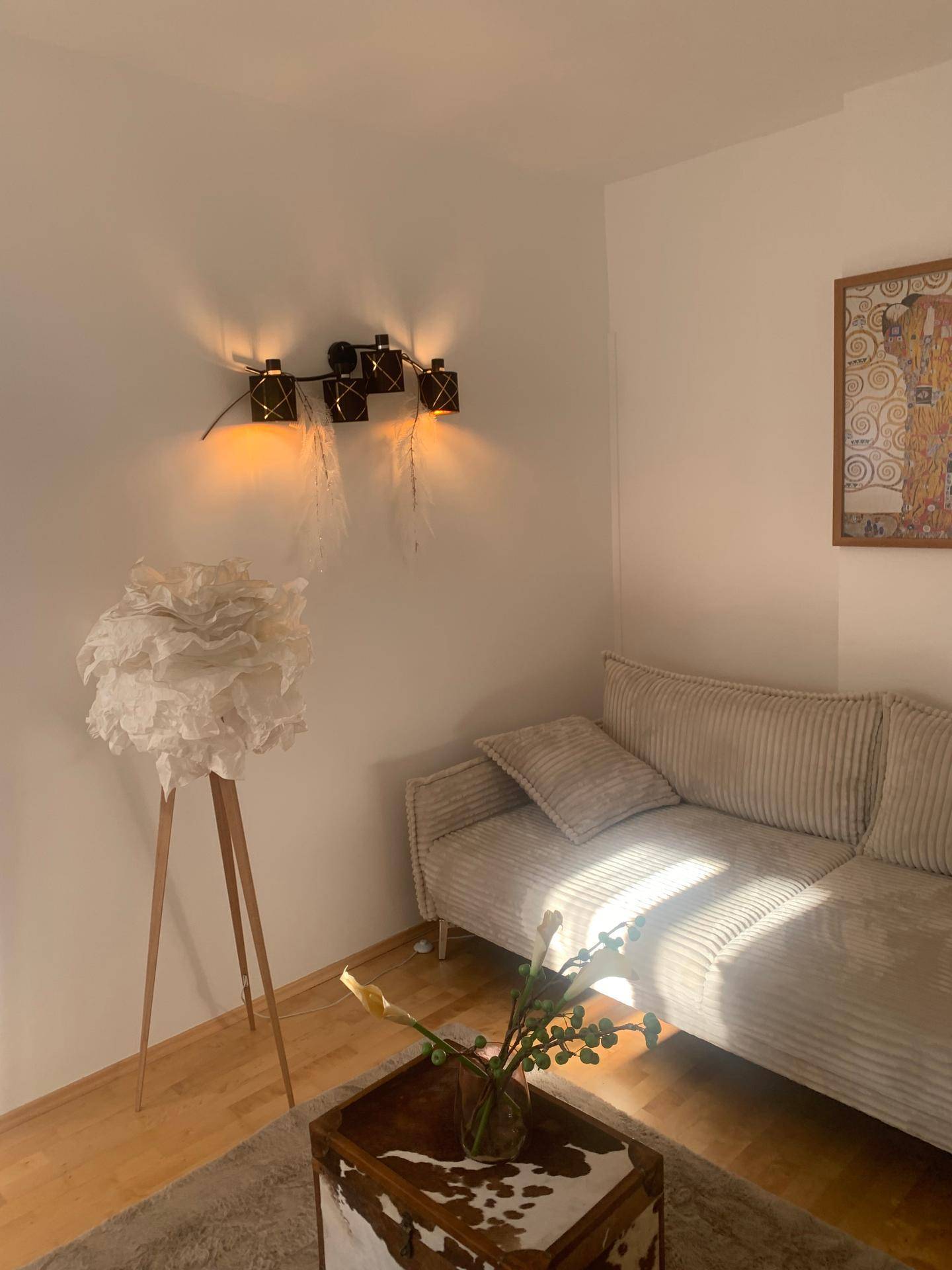 Heller Wohnbereich mit bequemem Sofa, einzigartiger Stehlampe und Kunstwerk an der Wand.