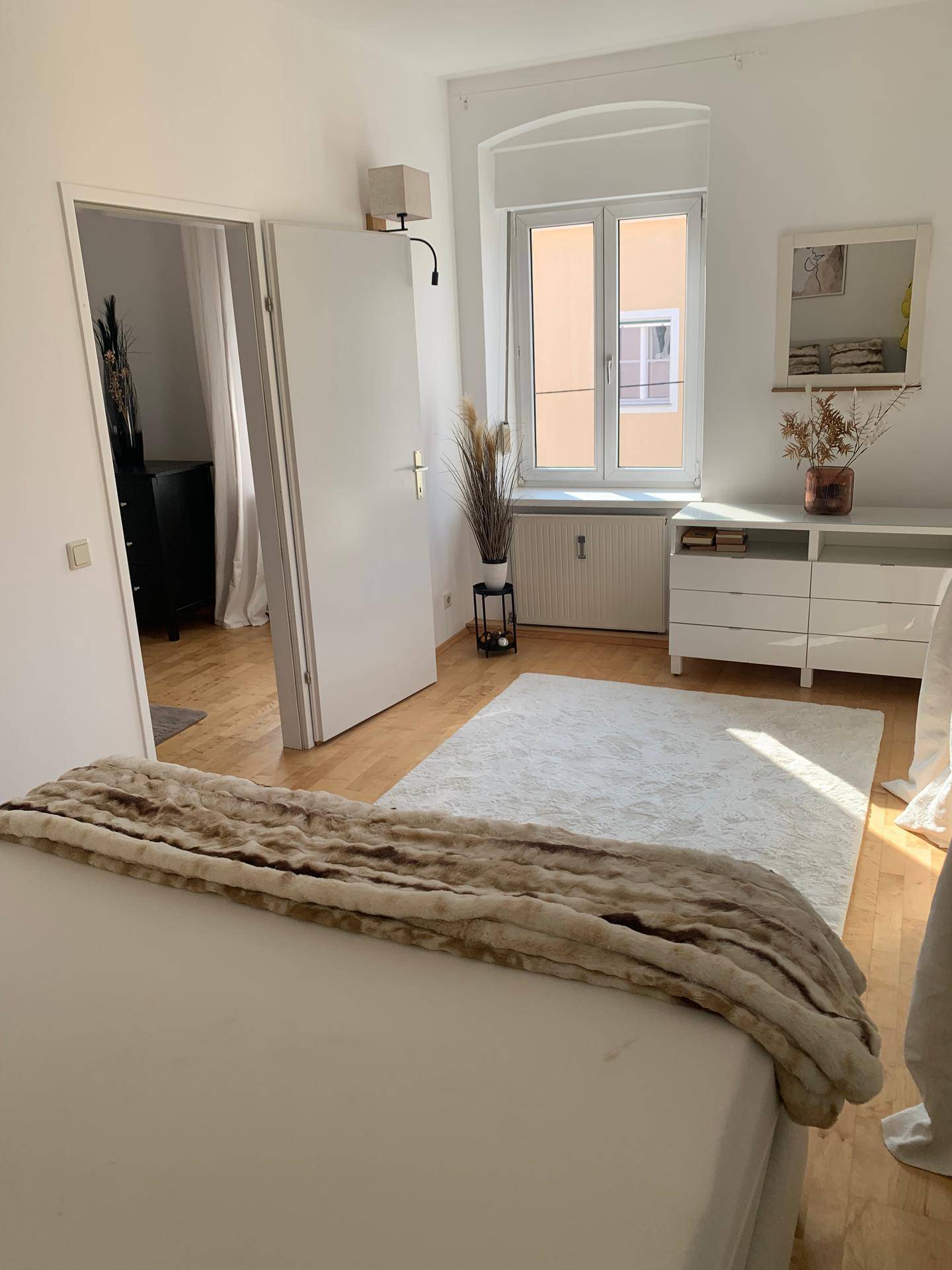 Geräumiges Schlafzimmer mit Doppelbett, Kommode und Zugang zu einem weiteren Raum.