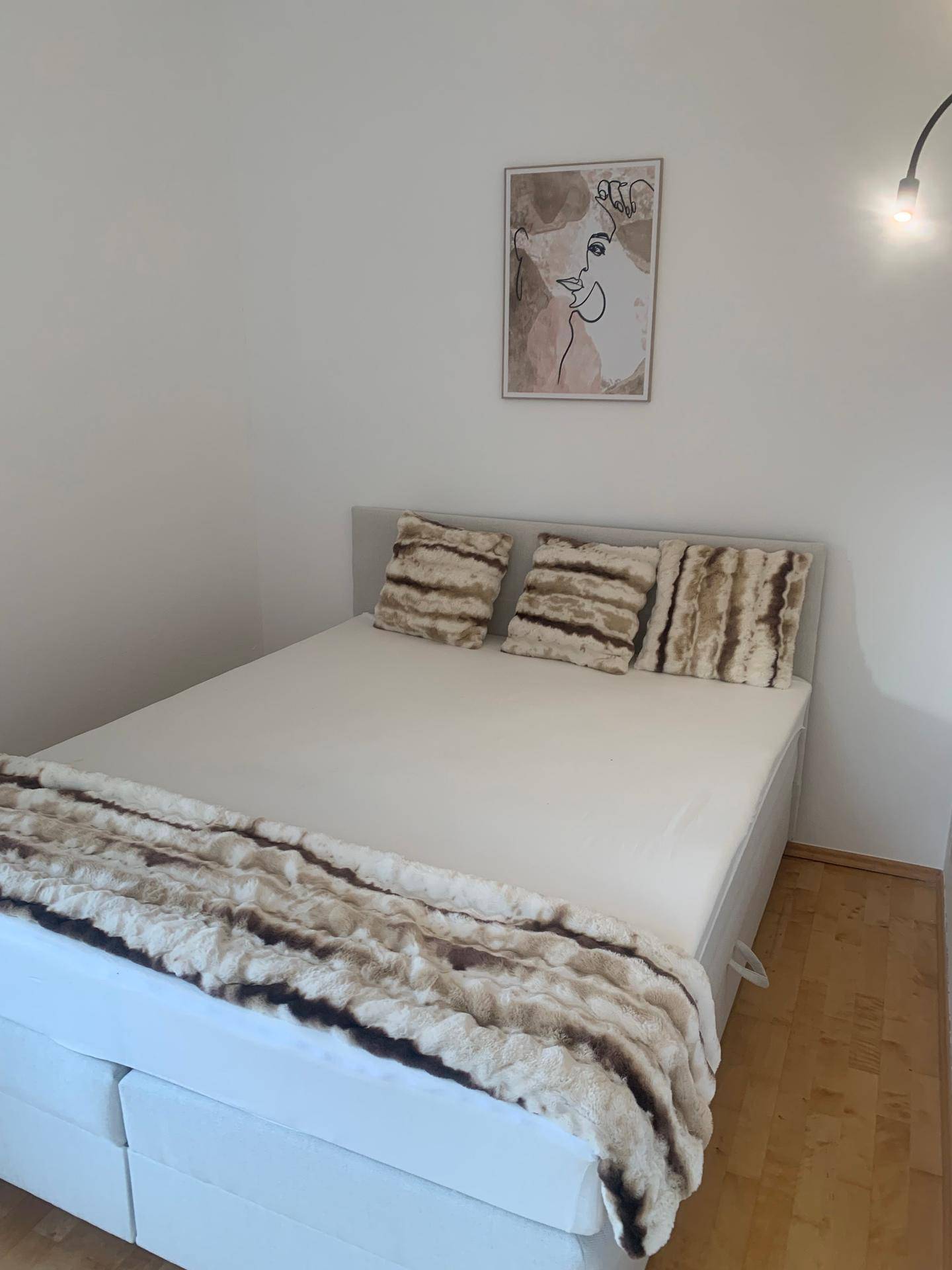 Gemütliches Schlafzimmer mit Doppelbett, weicher Fell-Decke und minimalistischer Wanddekoration.