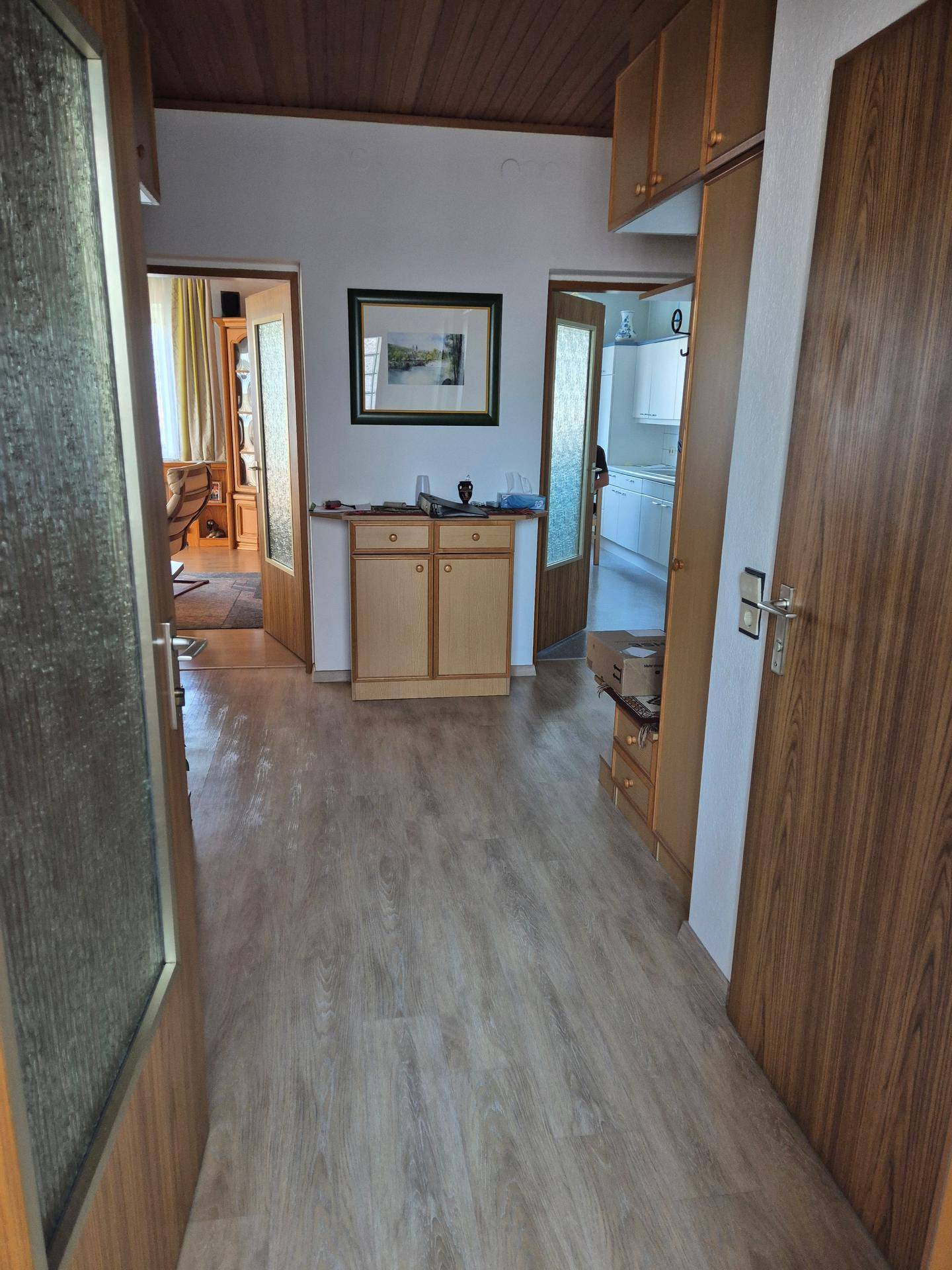 Heller Flur mit Holzdecke und Laminatboden, der zu verschiedenen Räumen führt.