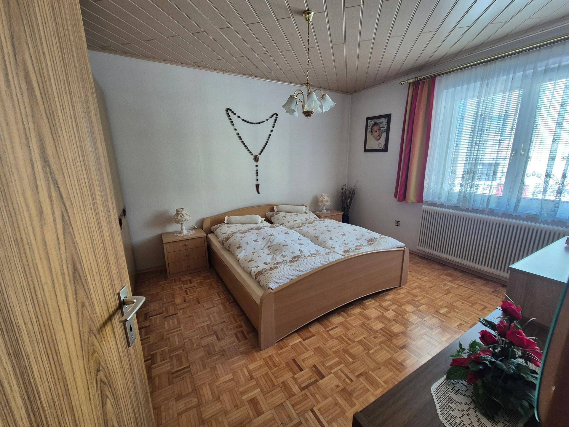 Helles Schlafzimmer mit Parkettboden, Holzdecke und Doppelbett, freundlich eingerichtet.
