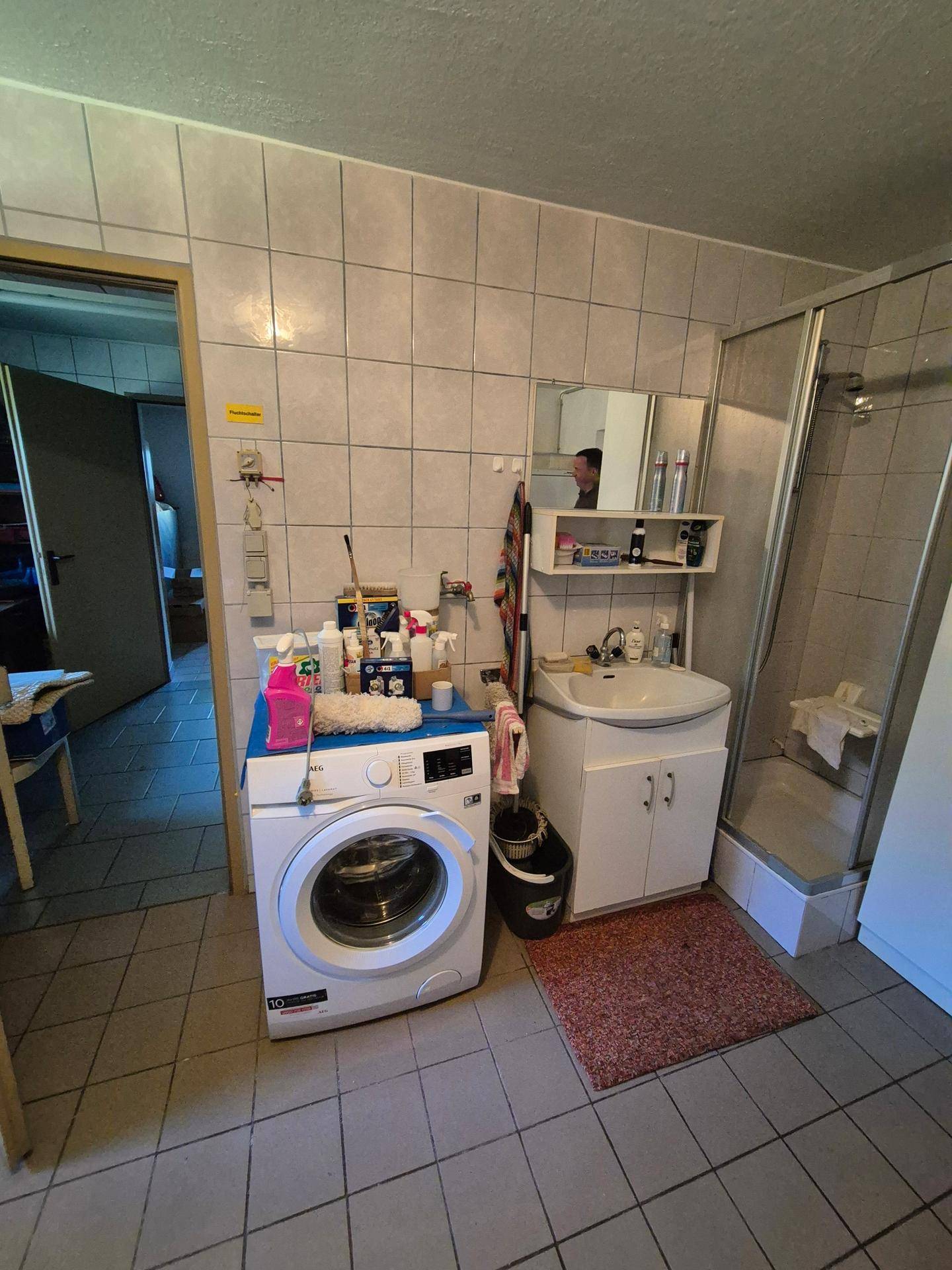 Badezimmer im Untergeschoss mit Dusche, Waschbecken und Waschmaschine.