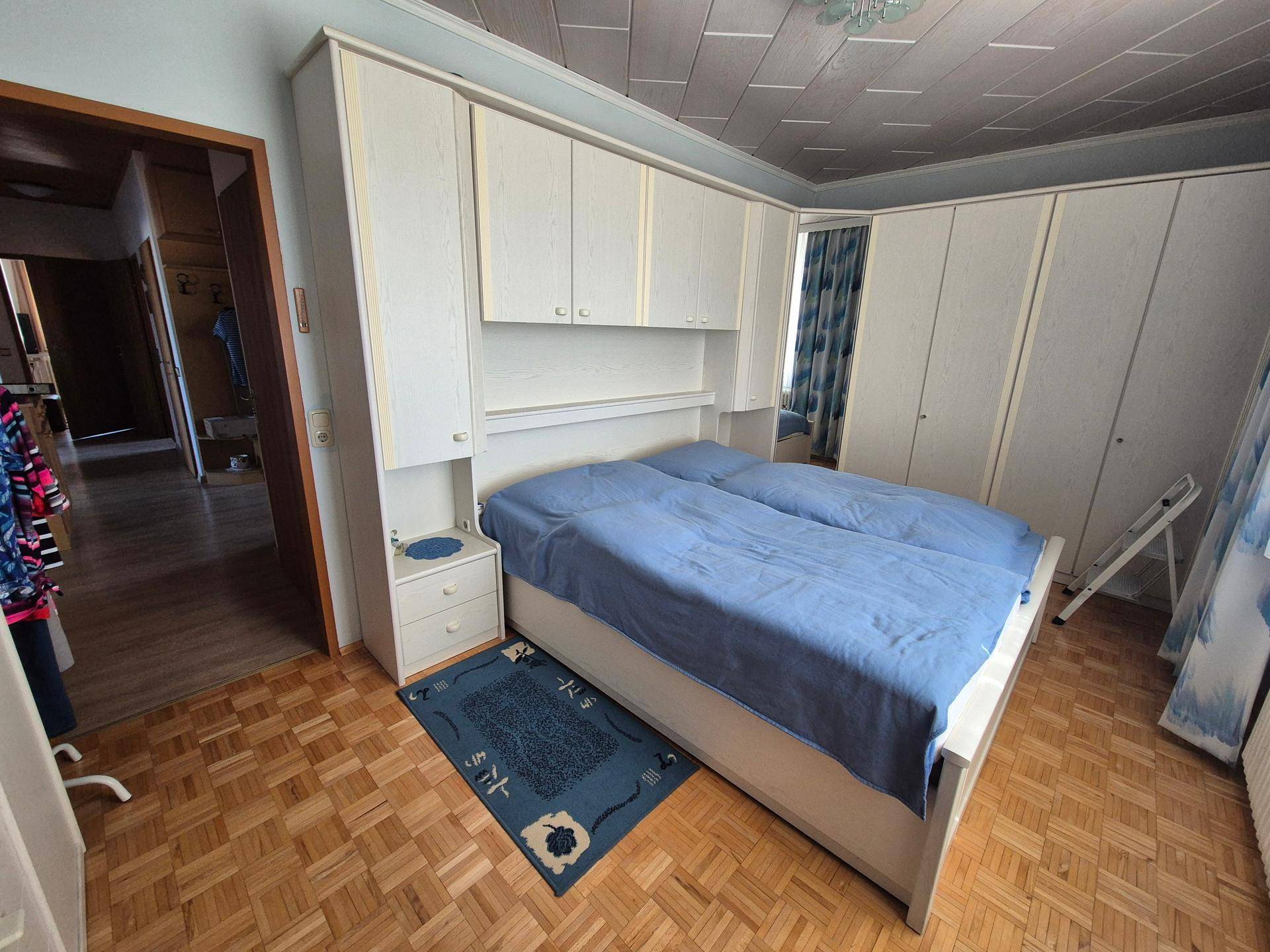 Schlafzimmer mit Parkettboden, Holzdecke und Einbauschrank, ausgestattet mit Doppelbett.