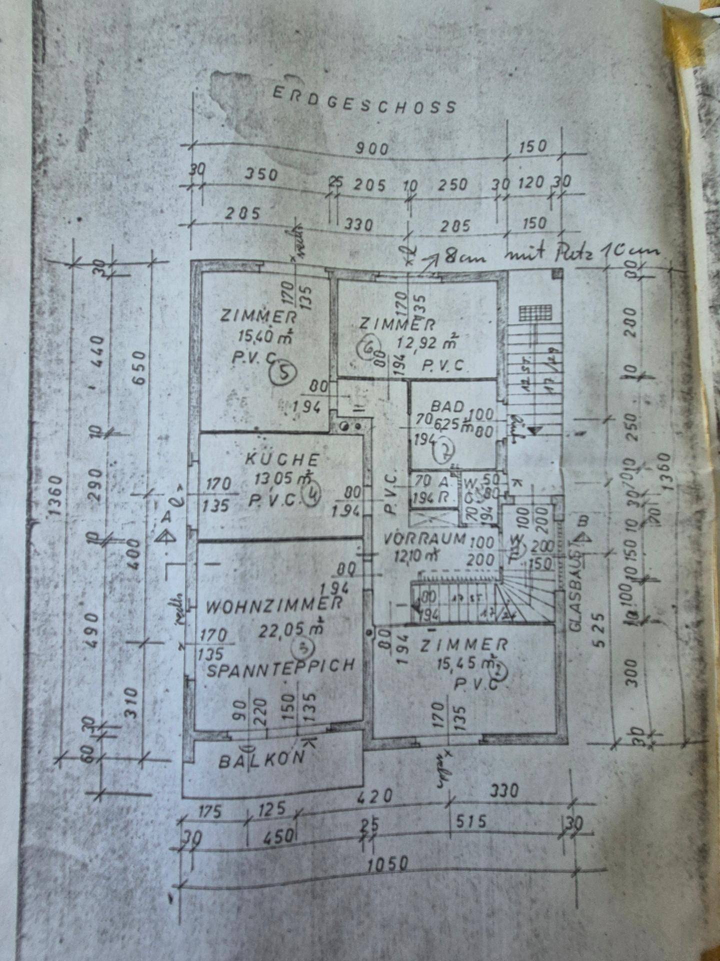 Grundriss des Erdgeschosses mit Wohnzimmer, Küche, Bad und drei Zimmern sowie Balkon.
