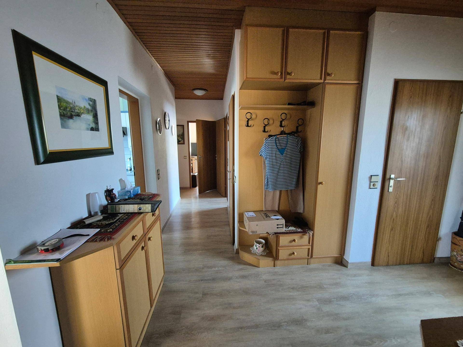 Langer Flur mit Laminatboden und Holzdecke, der verschiedene Wohnbereiche verbindet.