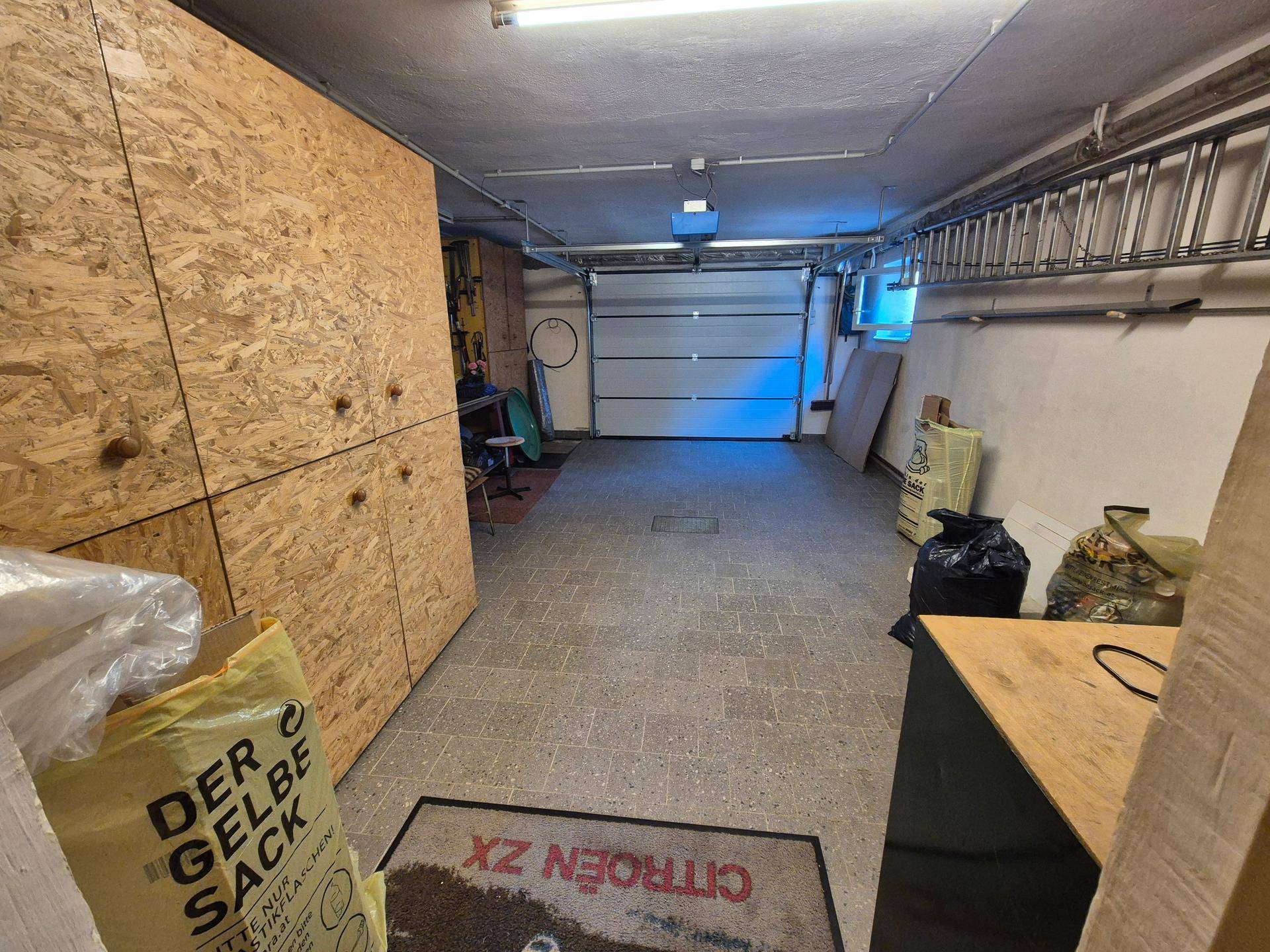 Geräumige Garage im Untergeschoss mit Rolltor und Stauraum an den Wänden.