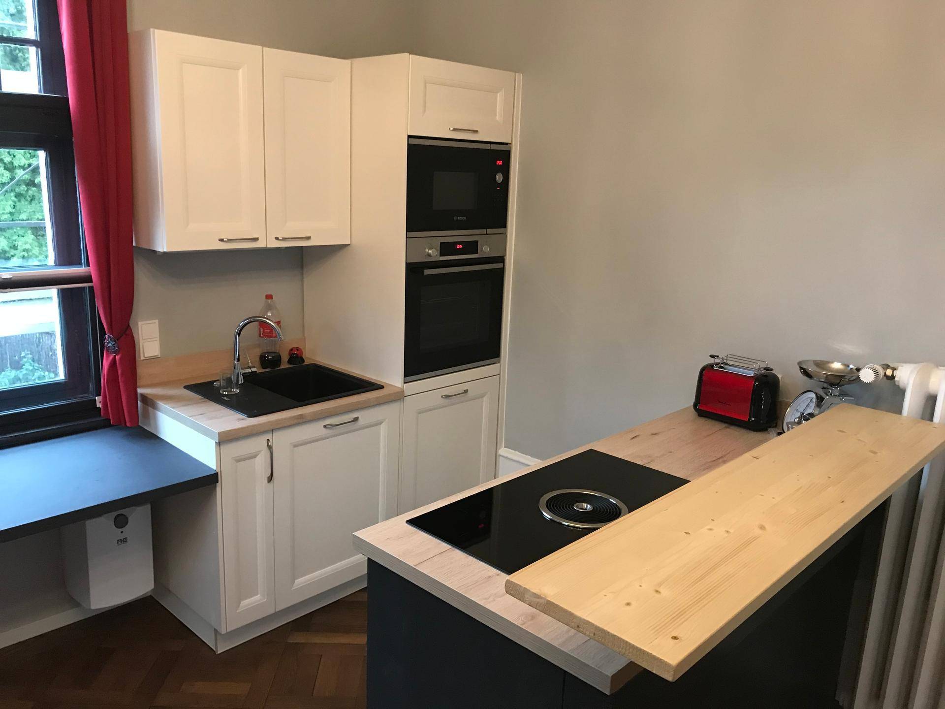 Moderne Küchenzeile mit integrierten Geräten, Induktionskochfeld und Holz-Arbeitsplatte.