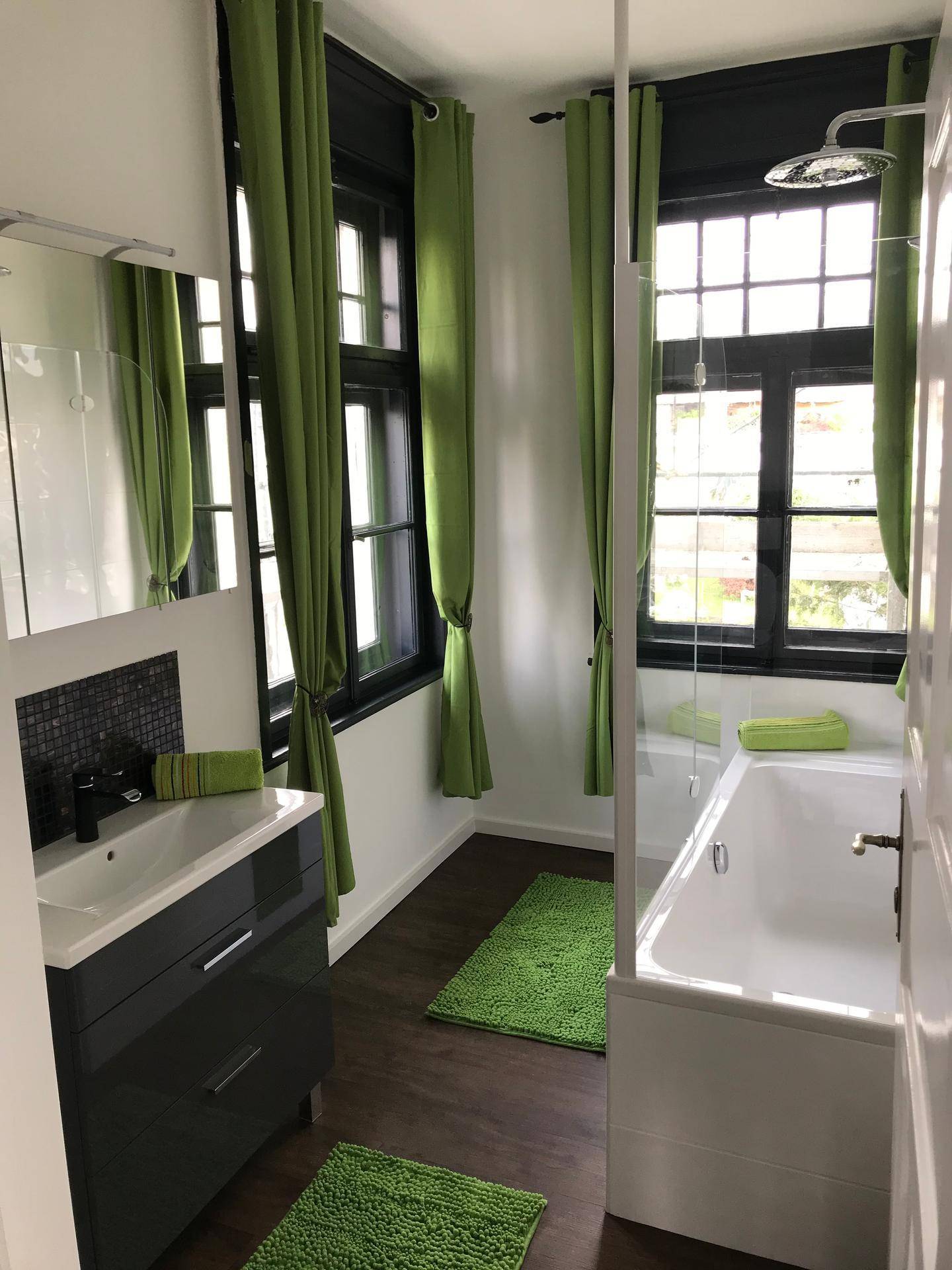 Modernes Badezimmer mit Badewanne, Duschfunktion, Einzelwaschbecken und einem Fenster für Tageslicht.
