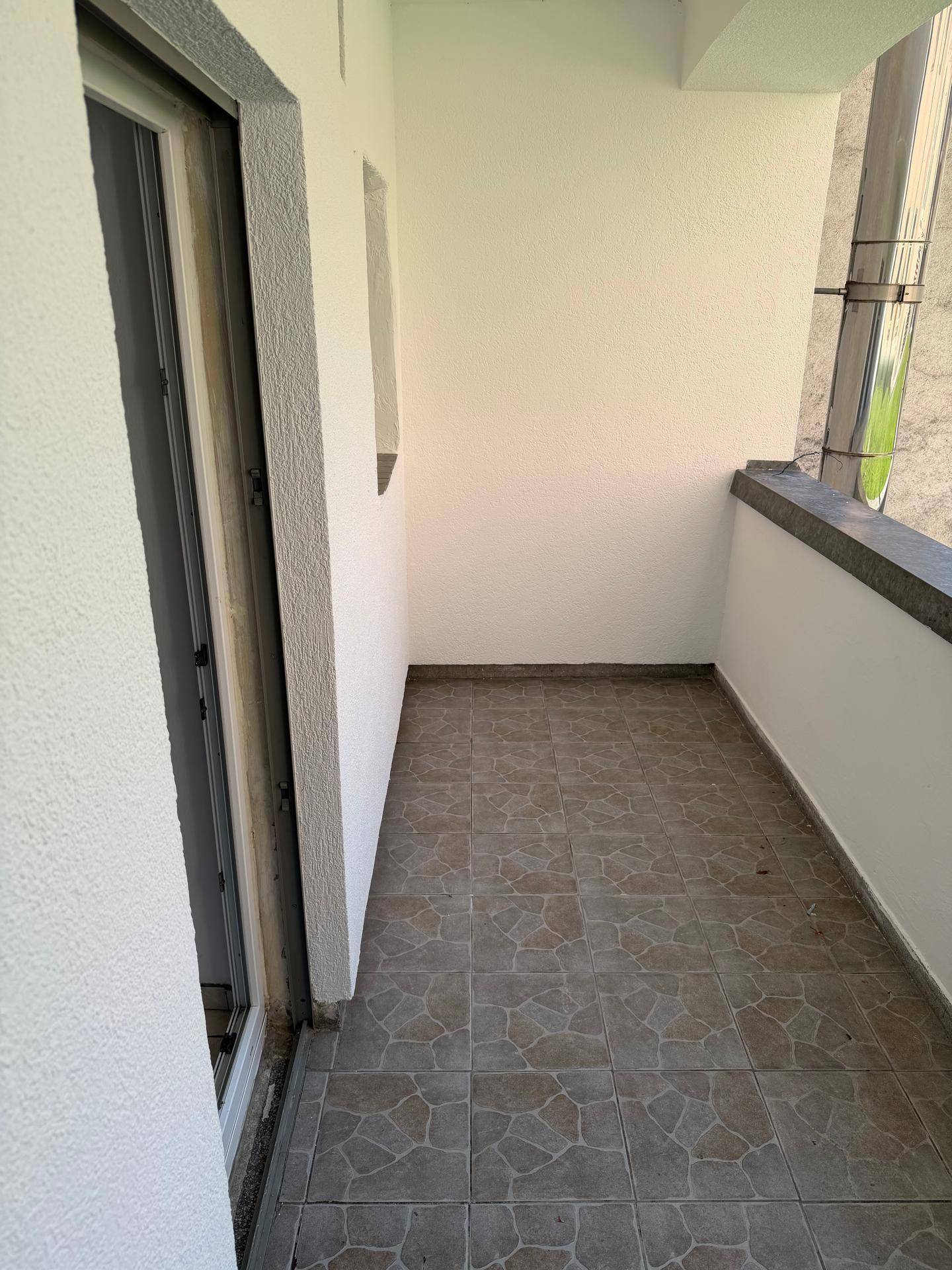 Gemütlicher Balkon mit Fliesenboden und weiß gestrichenen Wänden, ideal für entspannte Stunden.