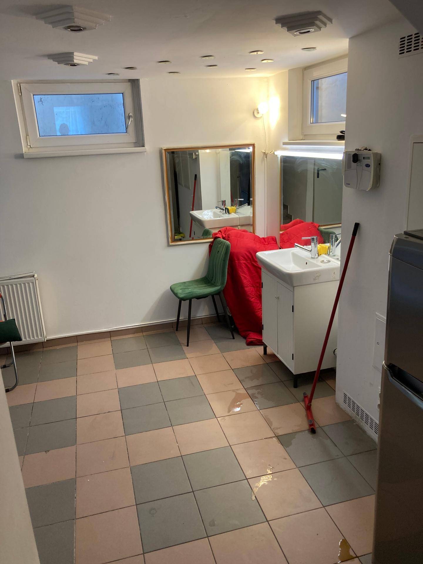 Mehrzweckraum im Keller mit Fliesenboden, Waschbecken und kleinen Fenstern.