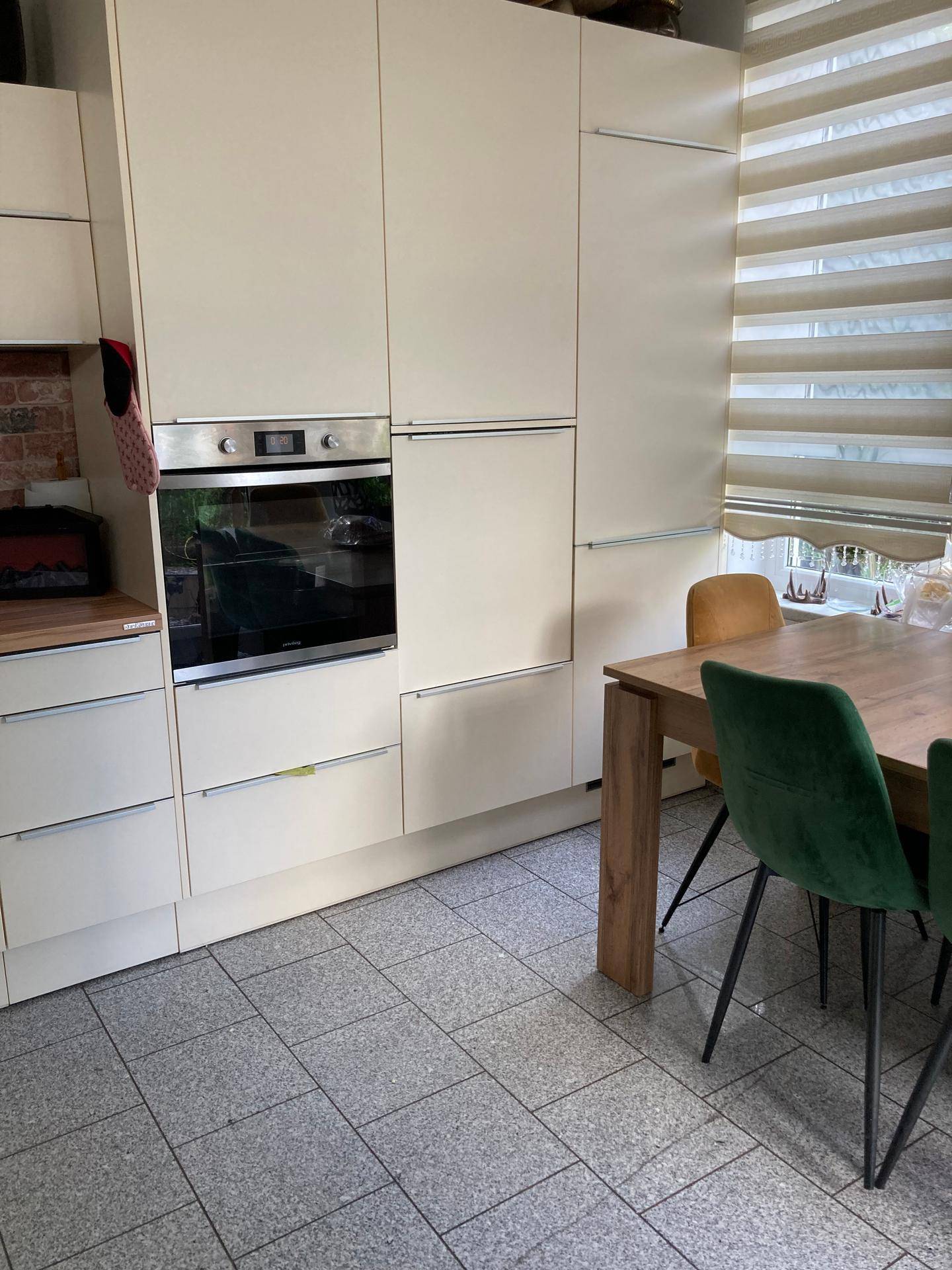 Moderne Einbauküche in Beige mit integriertem Backofen und Essbereich.