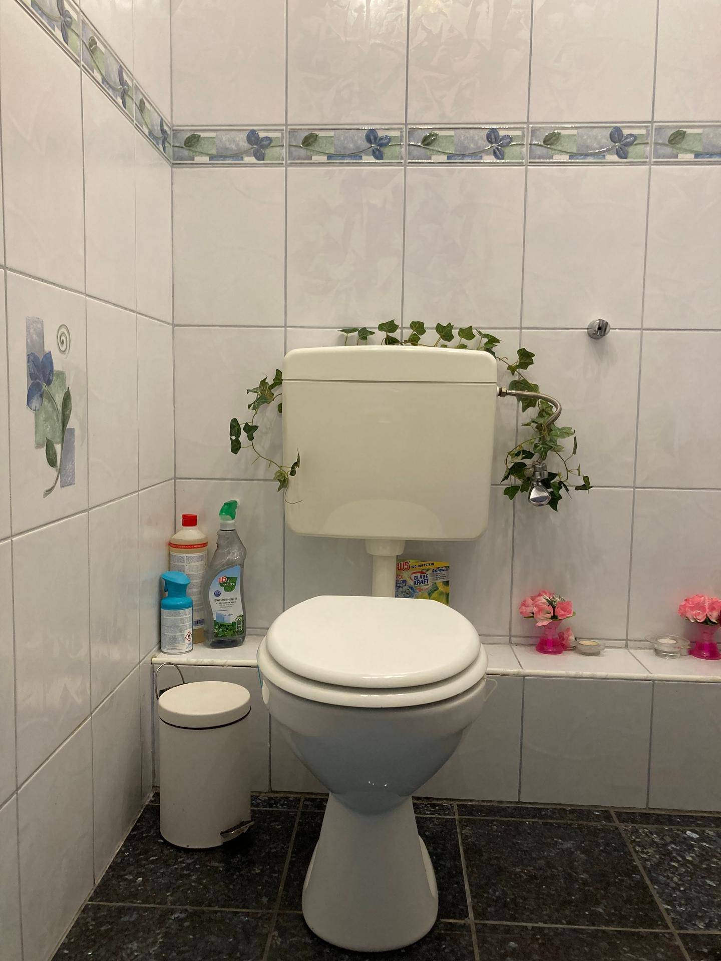 Kleines WC mit weißen Fliesen, Toilette und einfacher Dekoration.