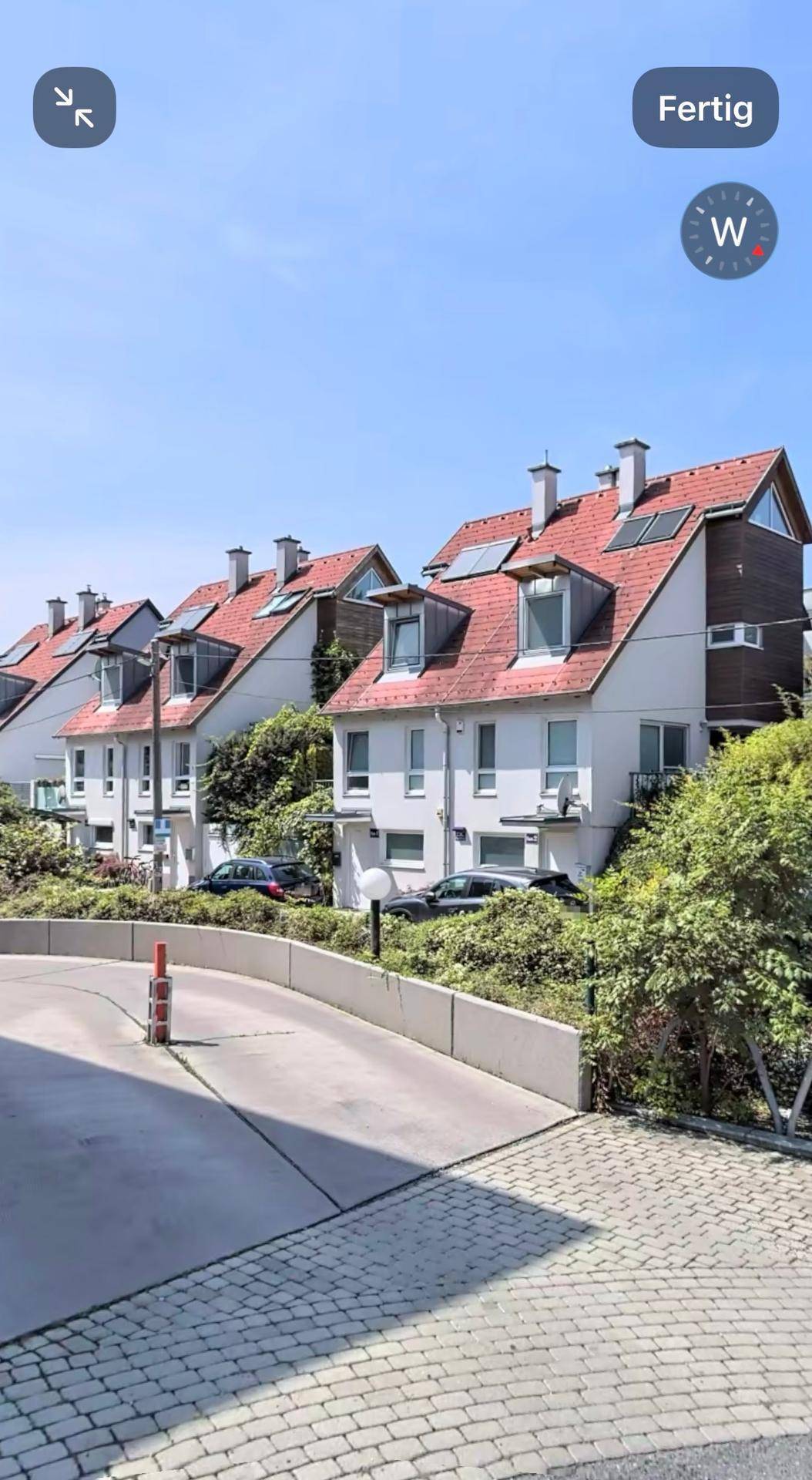 Reihe von Reihenhäusern mit roten Dächern und Solaranlagen unter blauem Himmel.