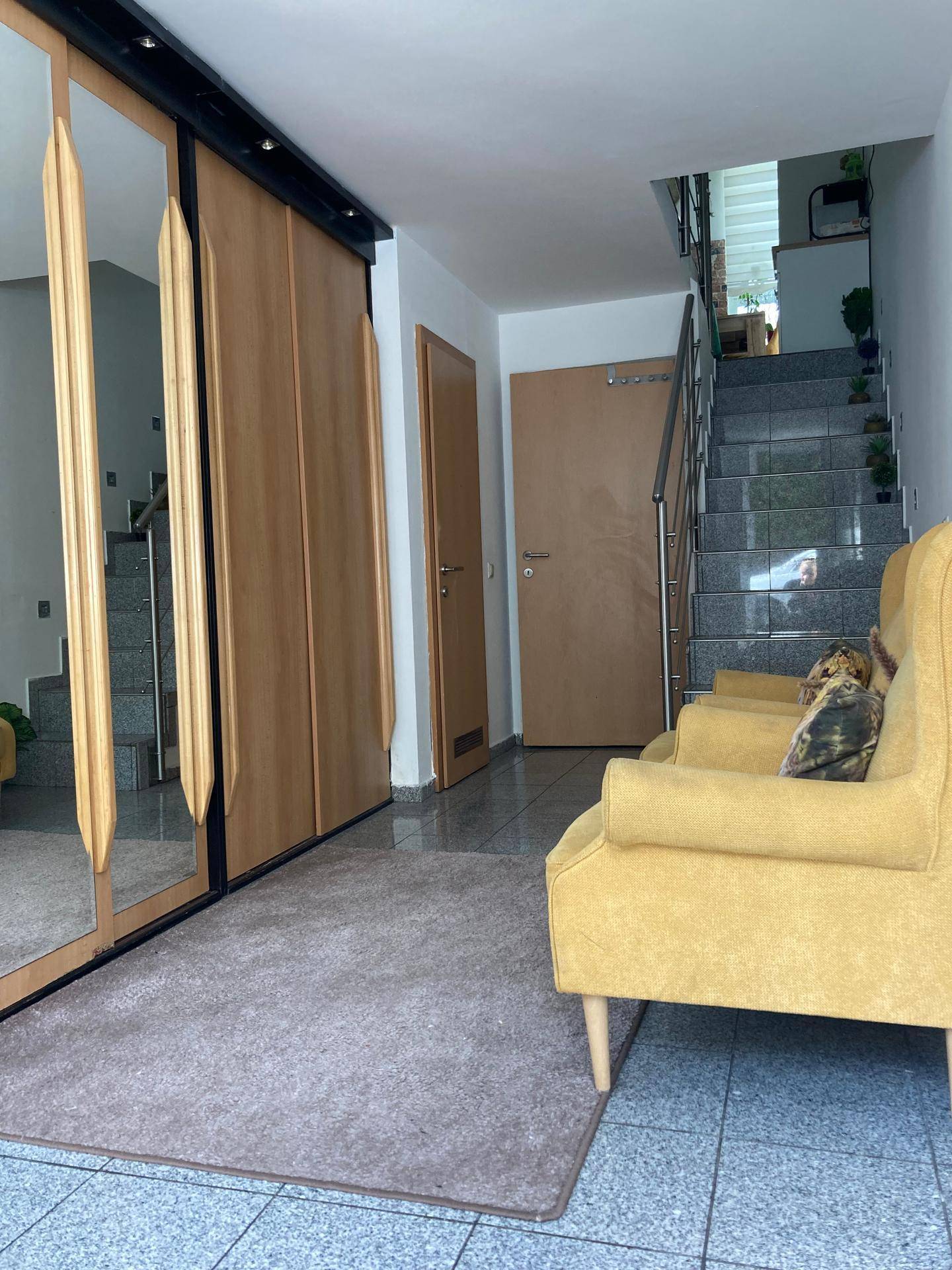 Heller Flur mit Spiegelschränken, Sitzgelegenheiten und Treppenaufgang.