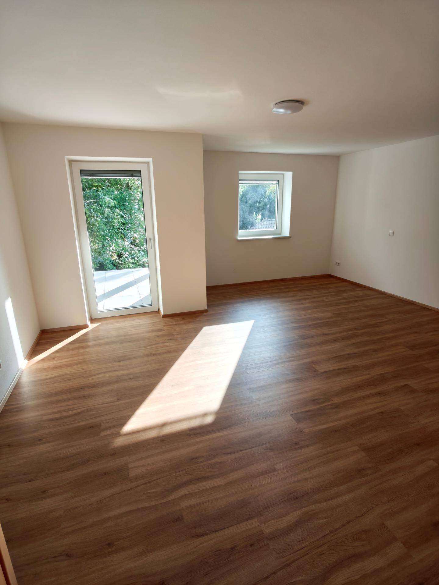 Geräumiges Schlafzimmer mit Laminatboden, viel Tageslicht und Zugang zur Terrasse.