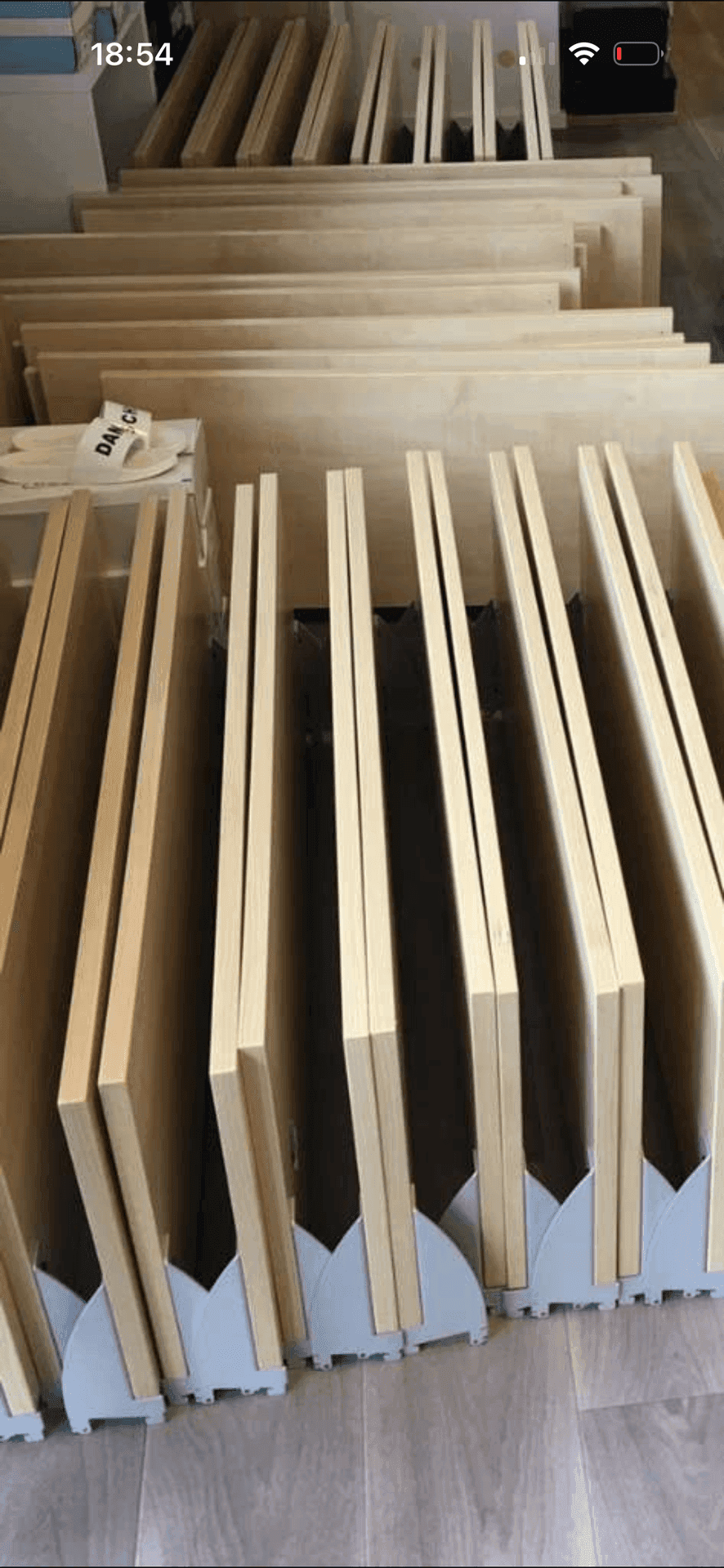 Gestapelte Holzplatten und Regalteile, bereit für die Montage in einem Lagerraum.