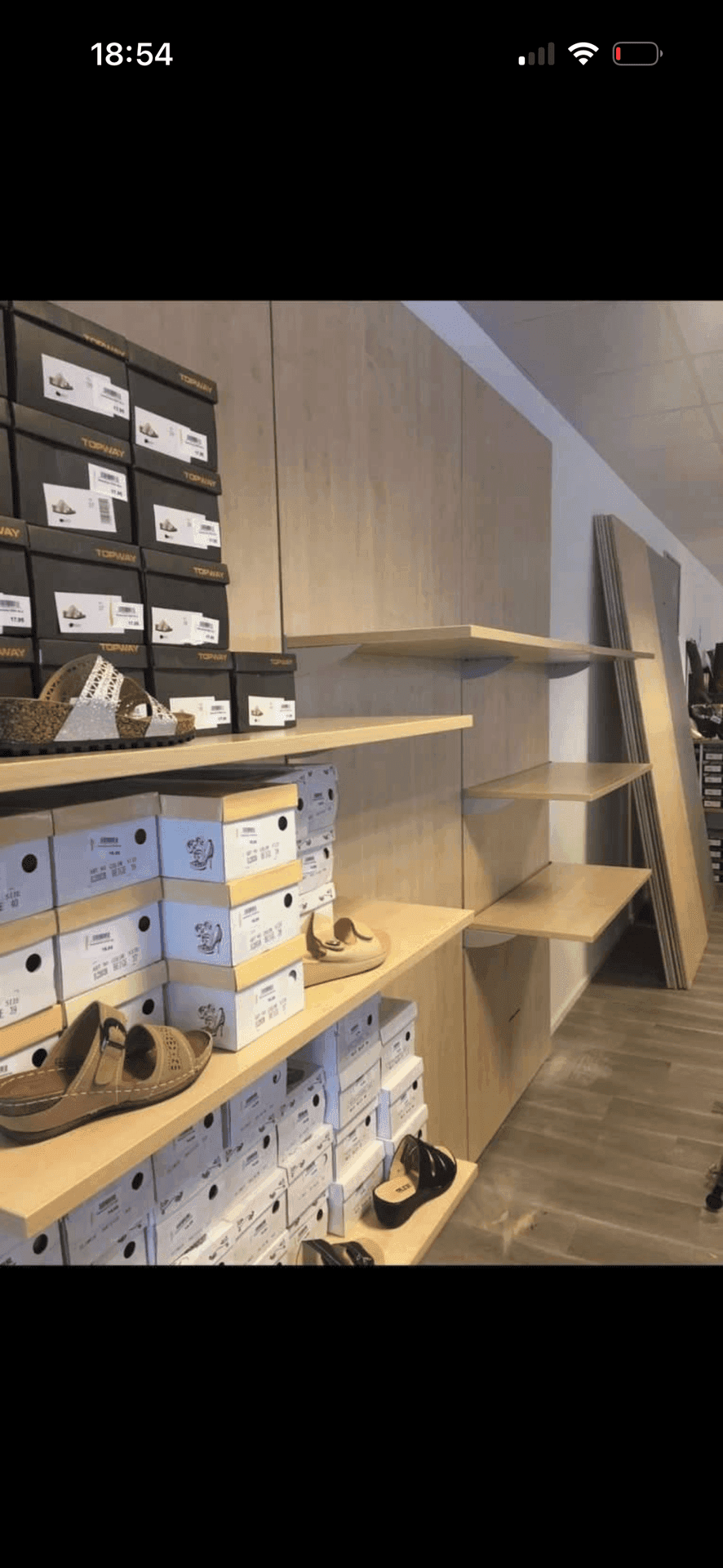 Holzregale mit Schuhkartons und ausgestellten Schuhen, Teil einer modernen Ladeneinrichtung.