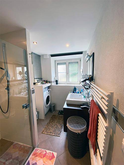 Modernes Badezimmer mit Dusche, Waschmaschine und beheiztem Handtuchhalter.