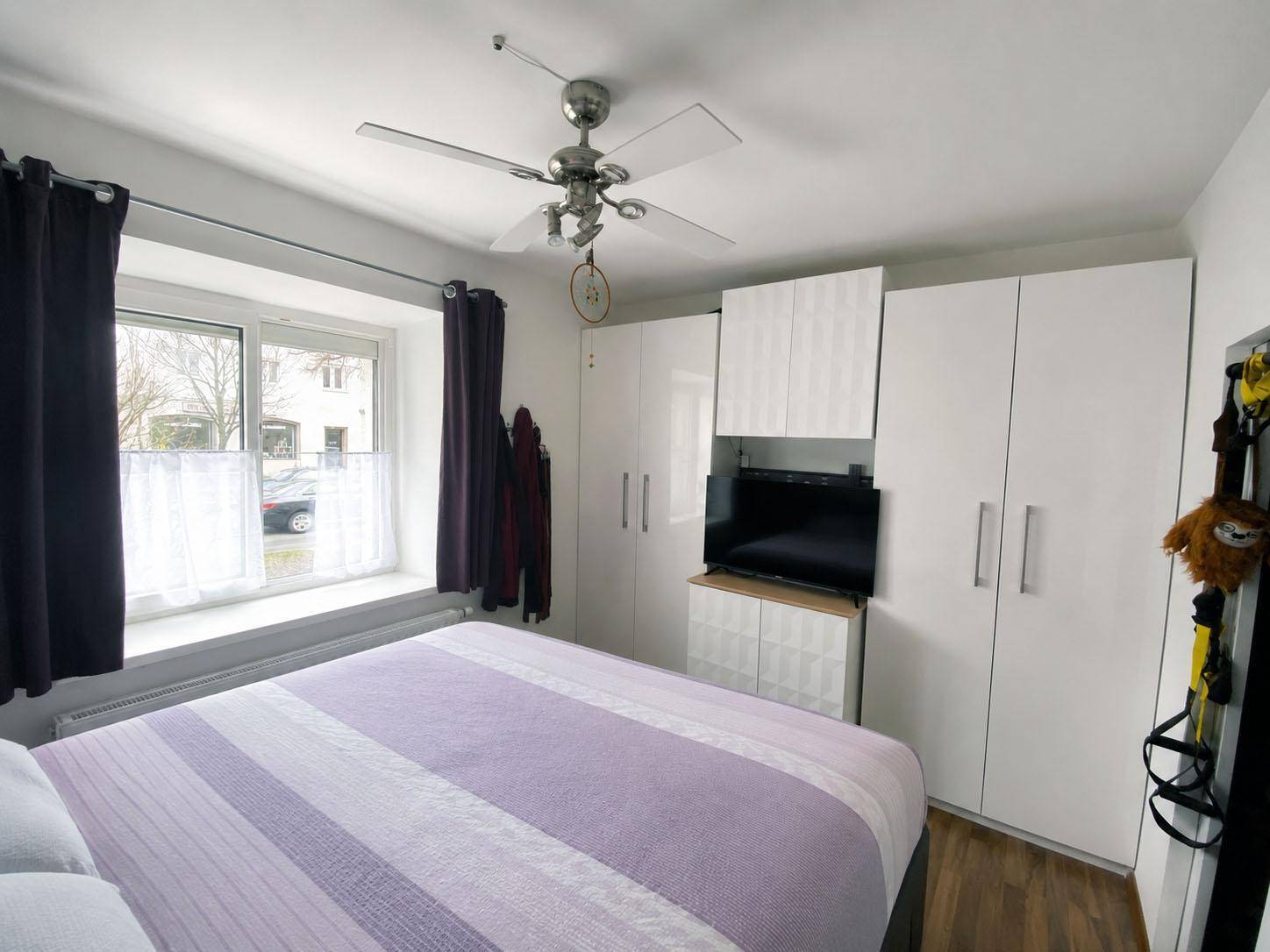 Schlafzimmer mit Doppelbett, Einbauschränken und Deckenventilator.
