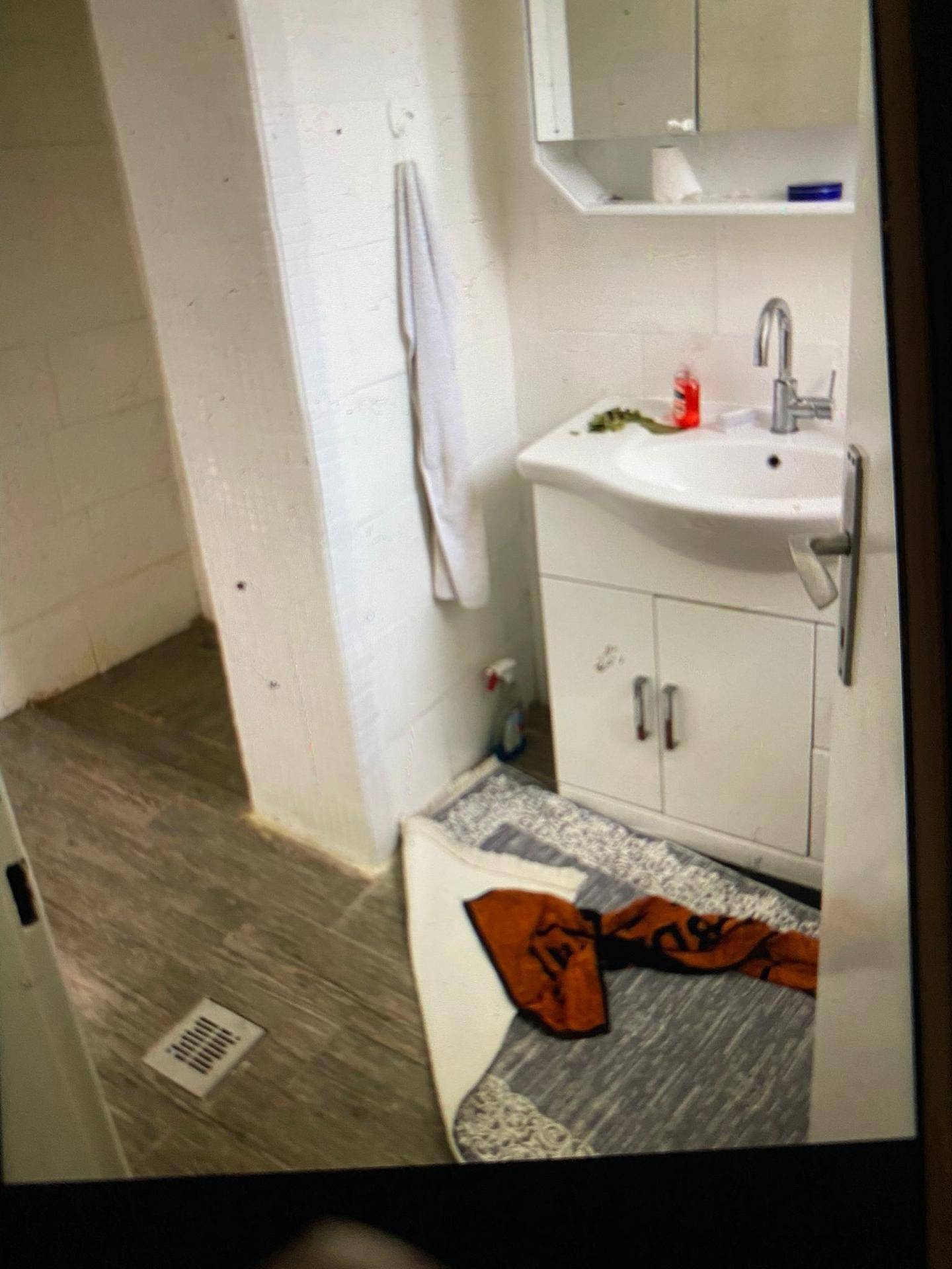 Badezimmer mit Waschbecken, Spiegelschrank und Duschbereich, Wände teilweise gefliest.