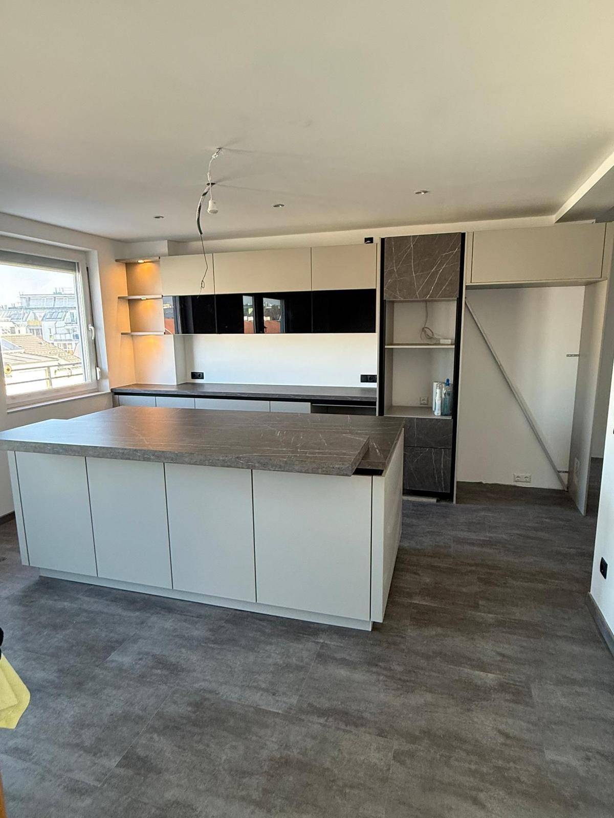 Moderne Einbauküche mit Kücheninsel und eleganten Arbeitsplatten, die viel Stauraum und Arbeitsfläche bietet.